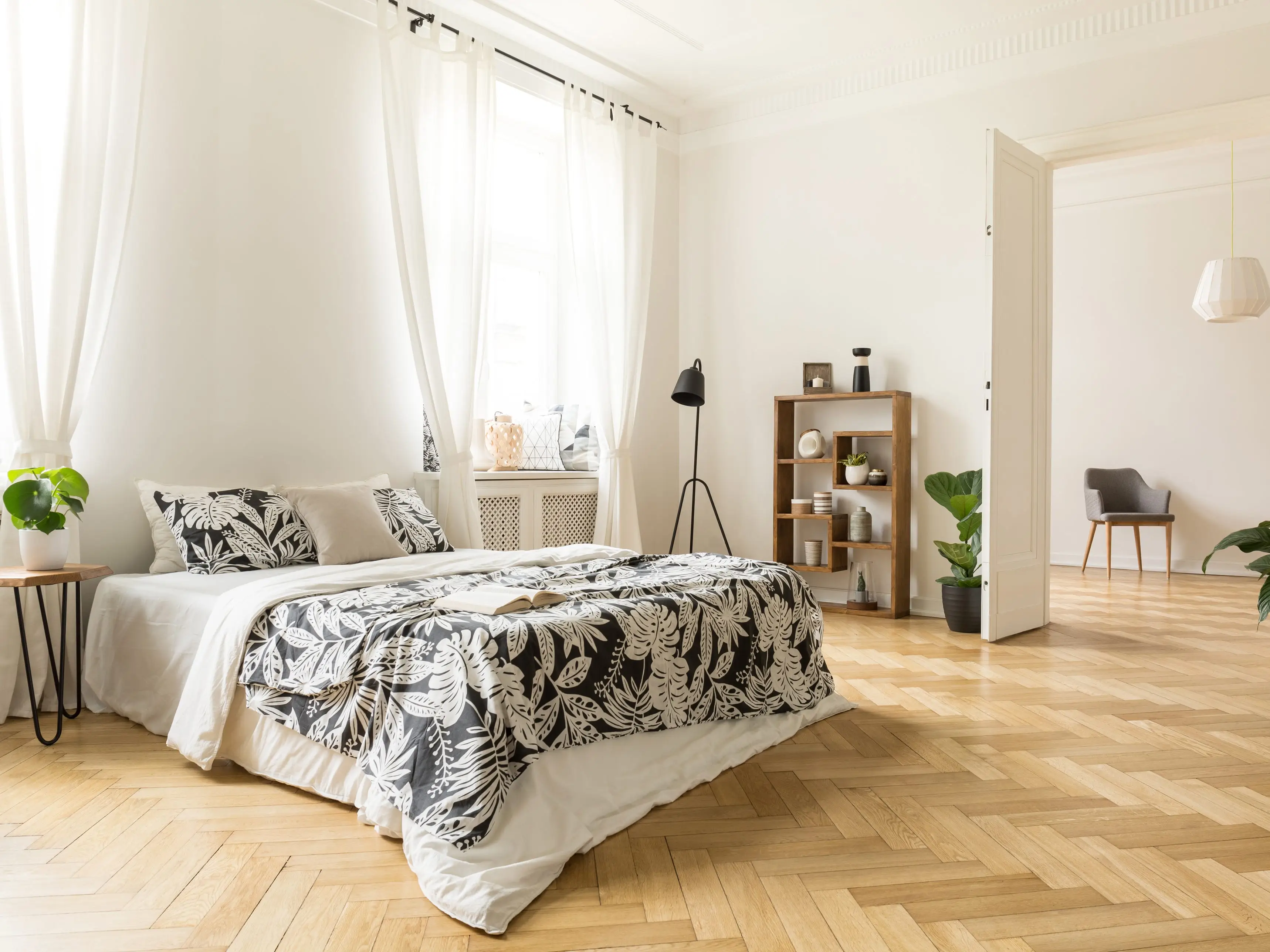 A white bedroom with herringbone wooden floors.