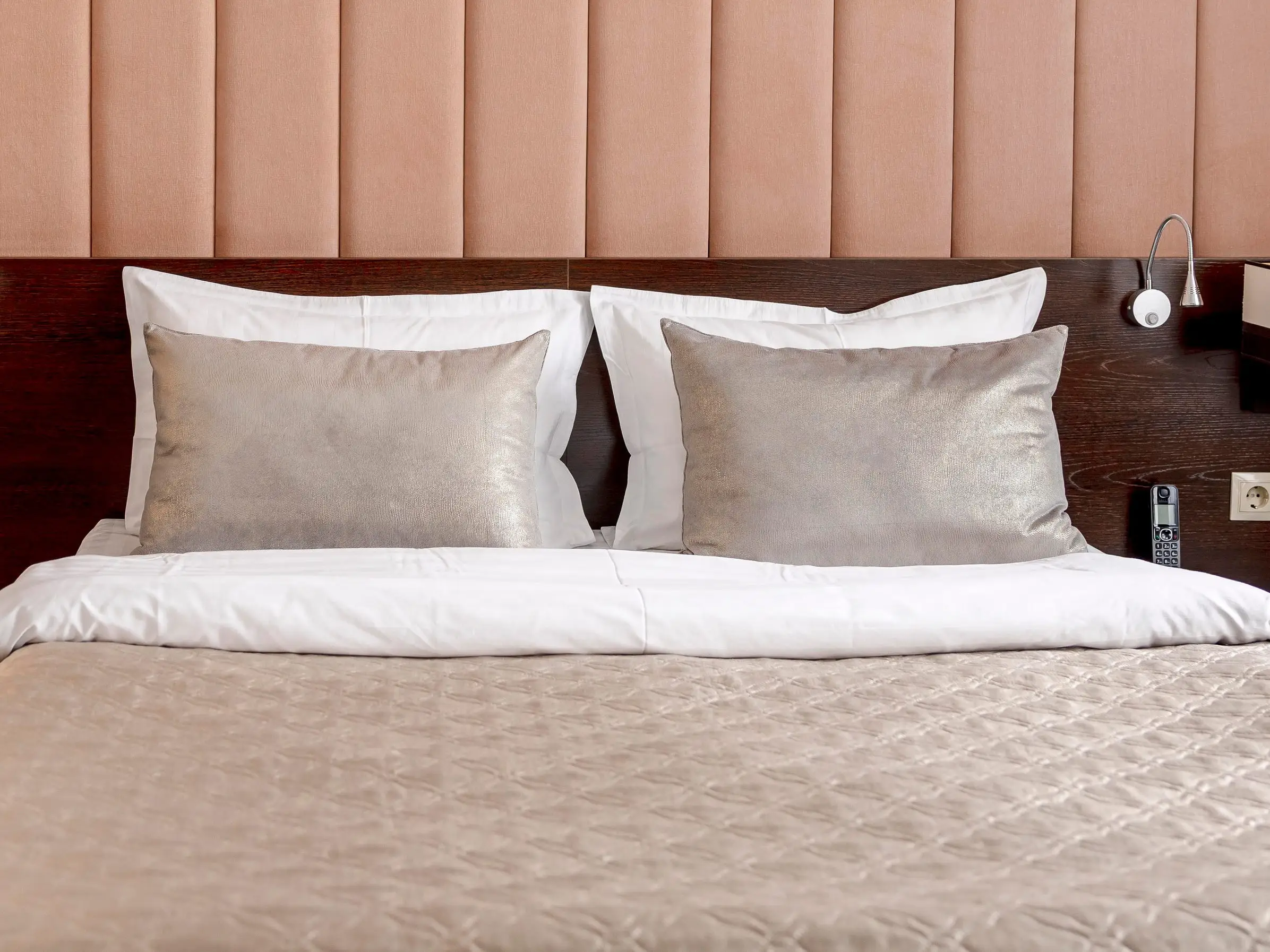 A bed with a metallic comforter and matching pillows.