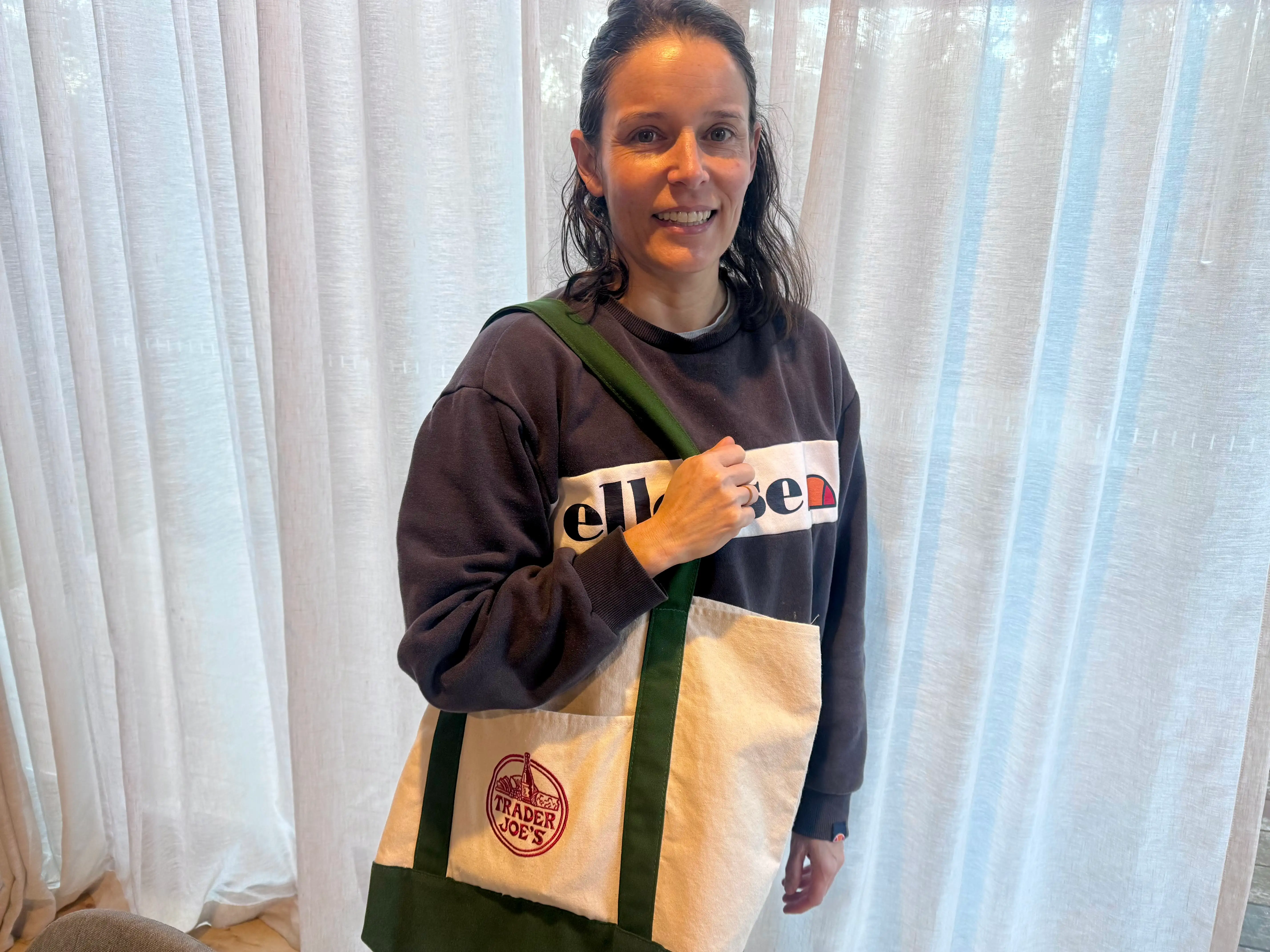 Woman smiling with trader joe's canvas tote over shoulder