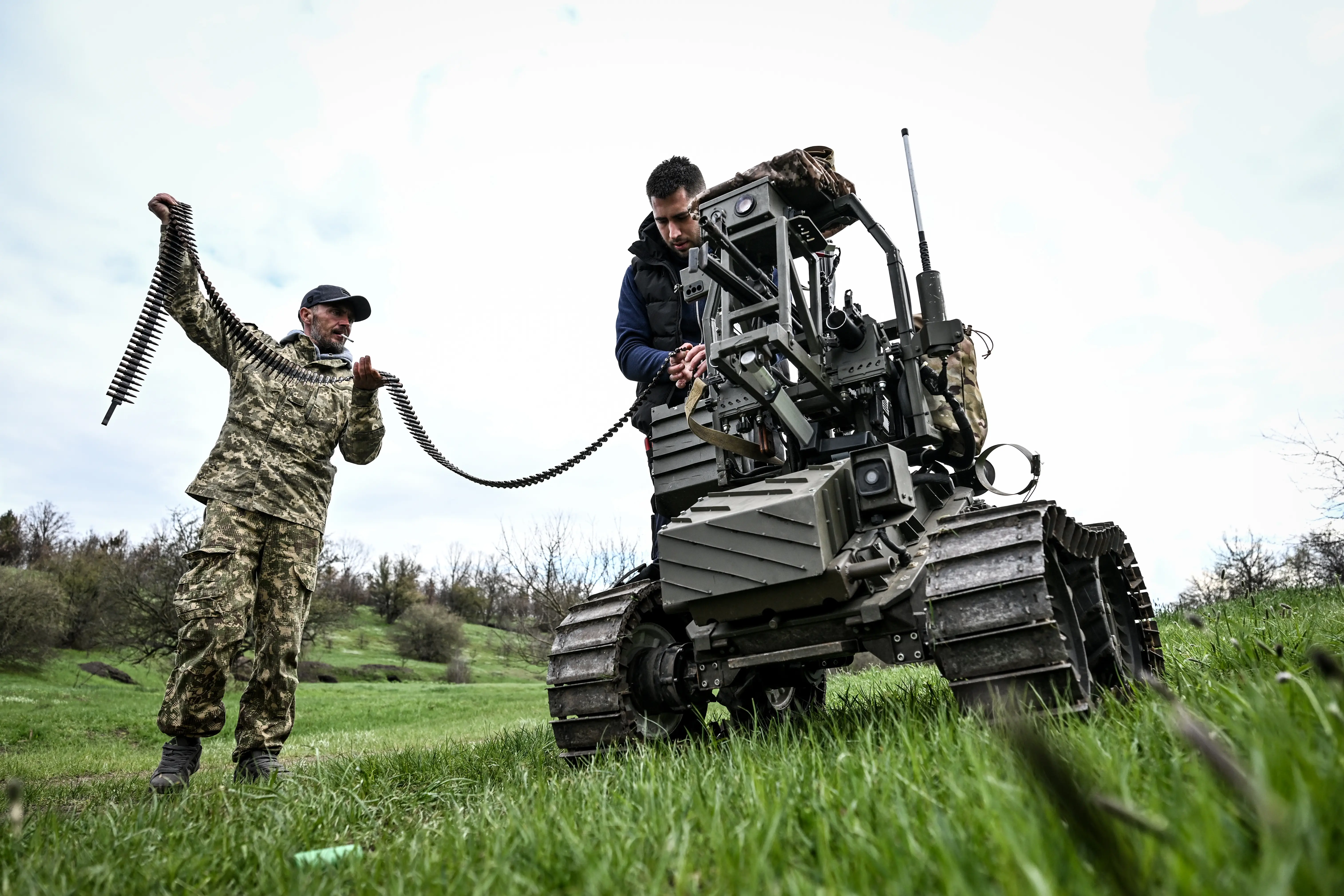 A soldier with the call sign ''Italian'' and design engineer Denys load a machine gun mounted on a ground robotic complex during trials at a training ground on April 10, 2026.