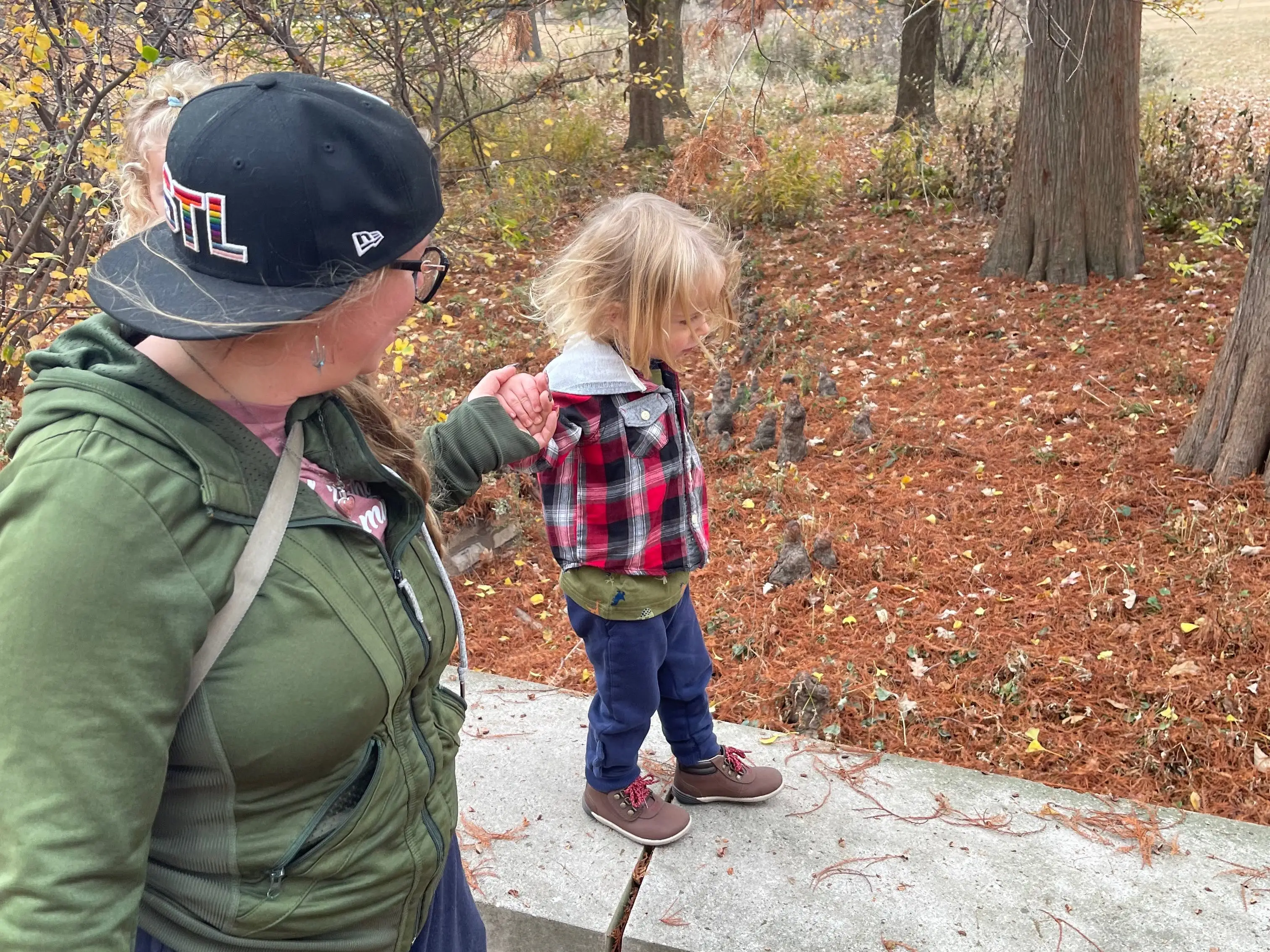 The author's wife and son holding hands and walking around a park on a fall day.