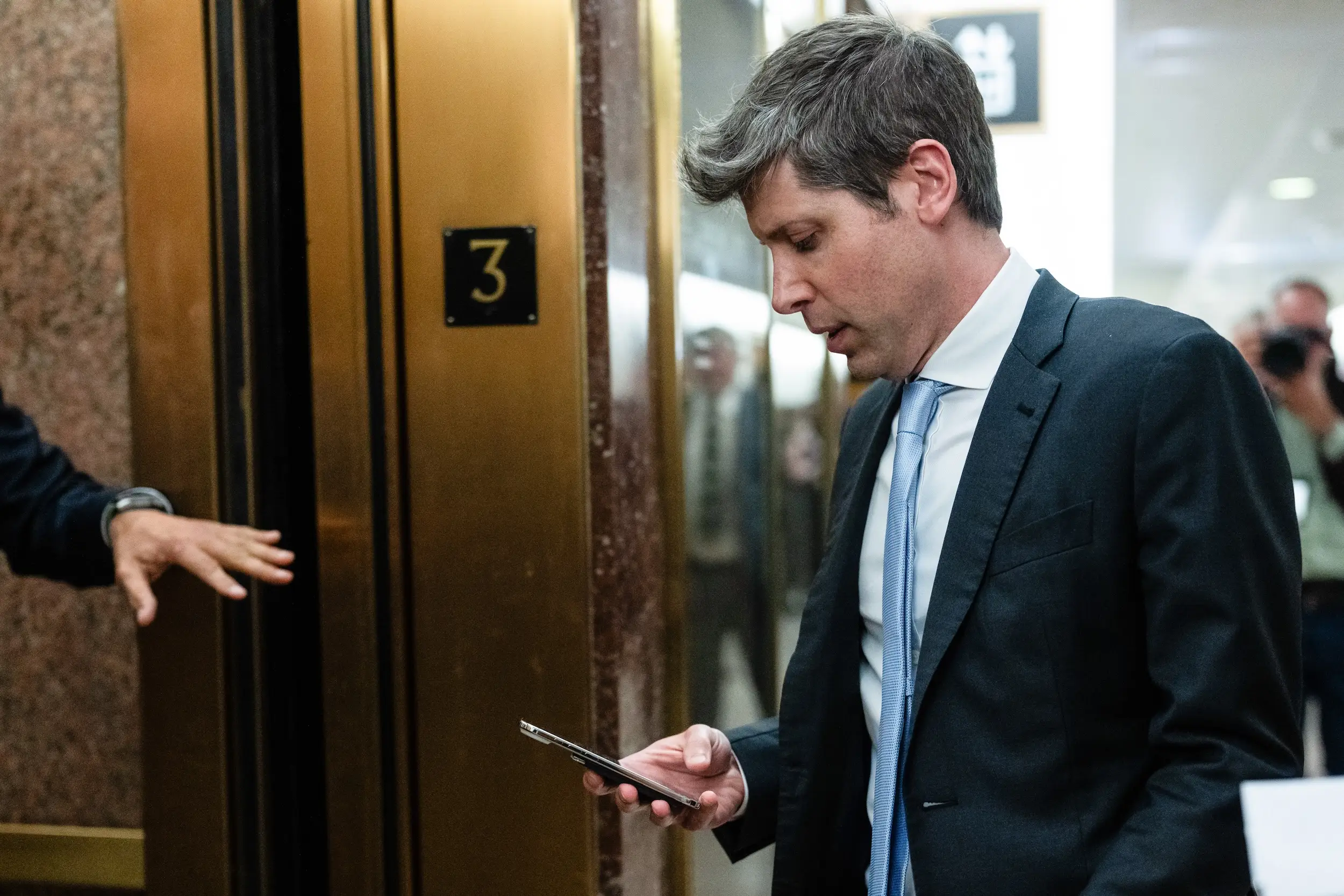 Sam Altman looks at his phone while walking around Capitol Hill