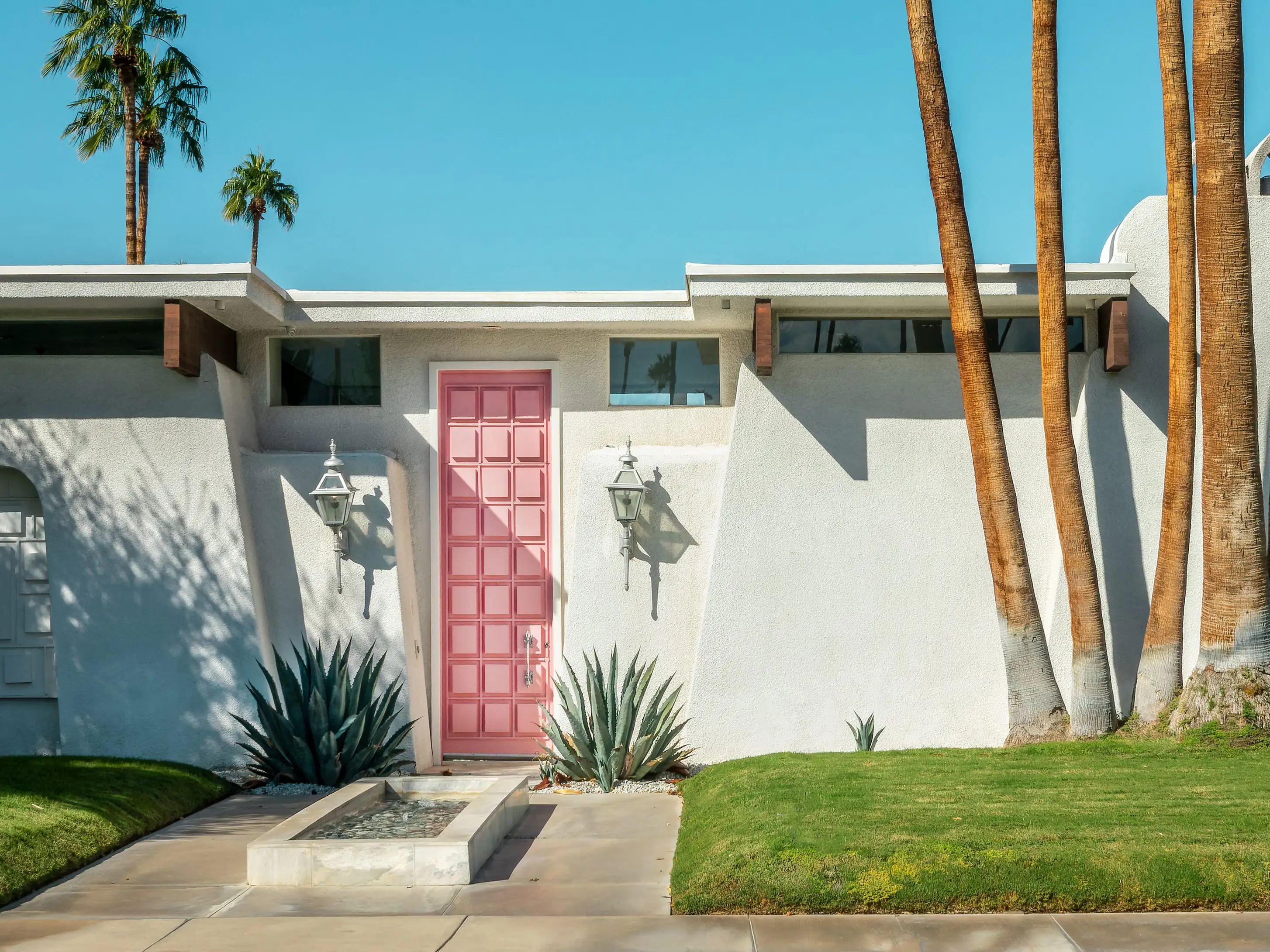 A modern mid-century home with a colorful pink door in Palm Springs, California.