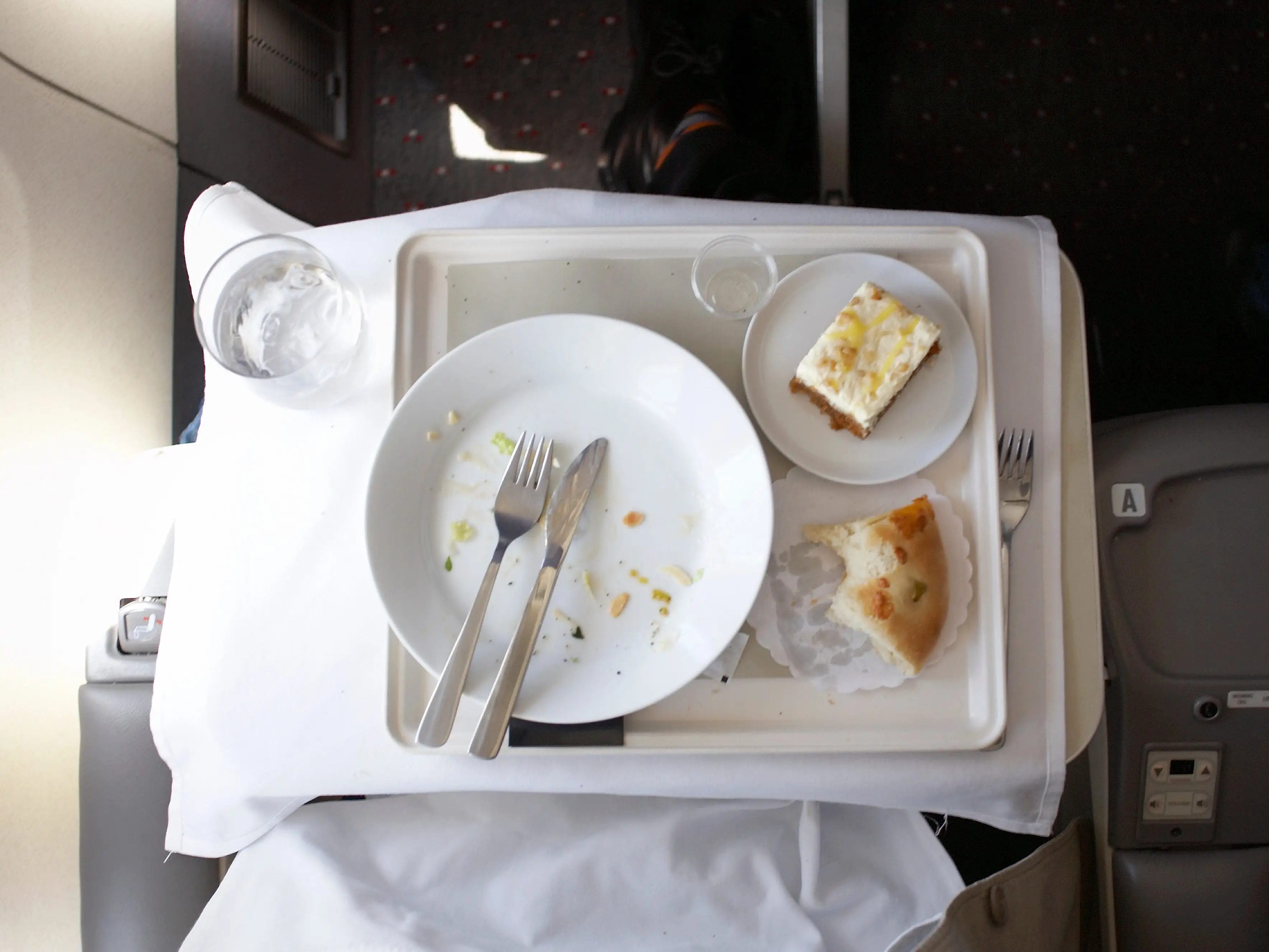 An empty plate that food has been eaten off of, along with cutlery and dessert.