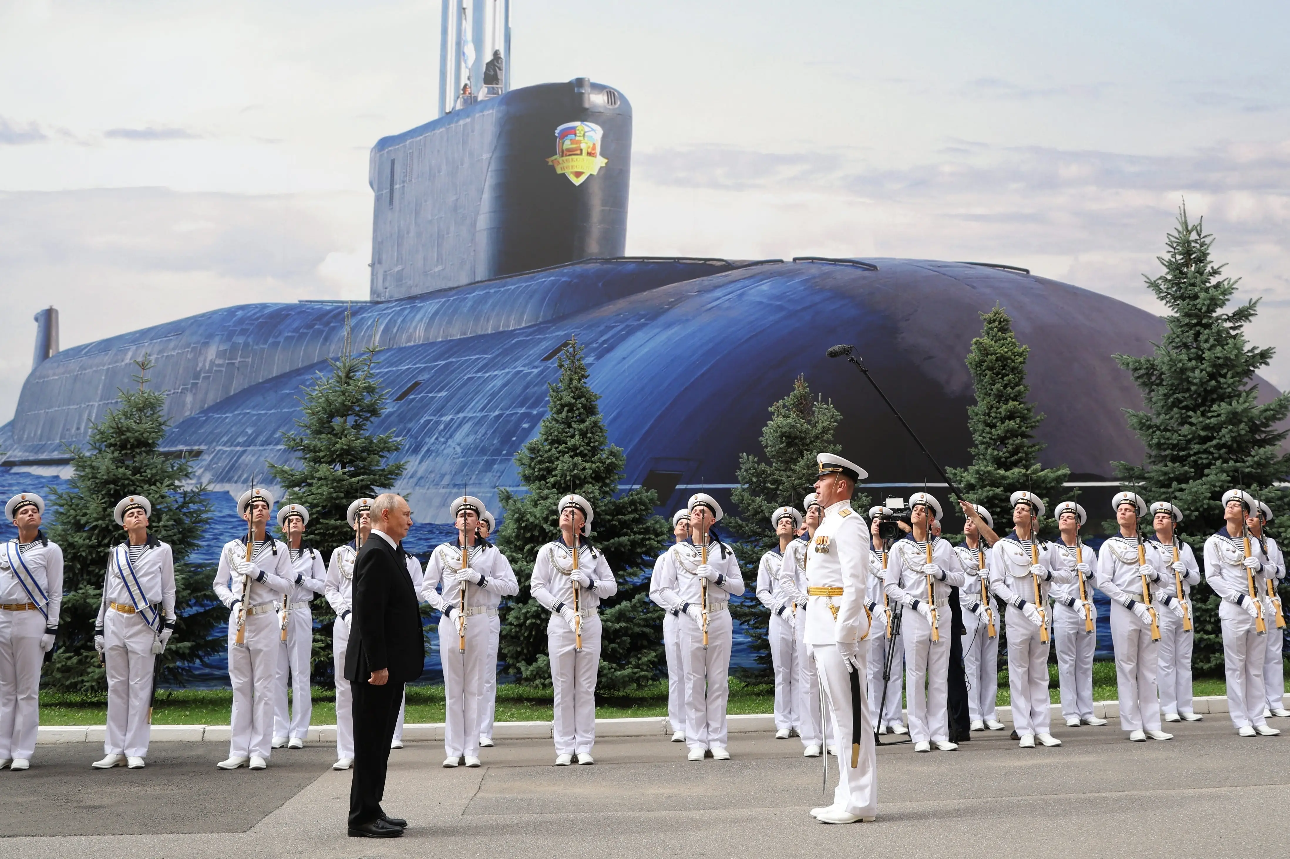 Putin is greeted by a naval officer and a small contingent of sailors.