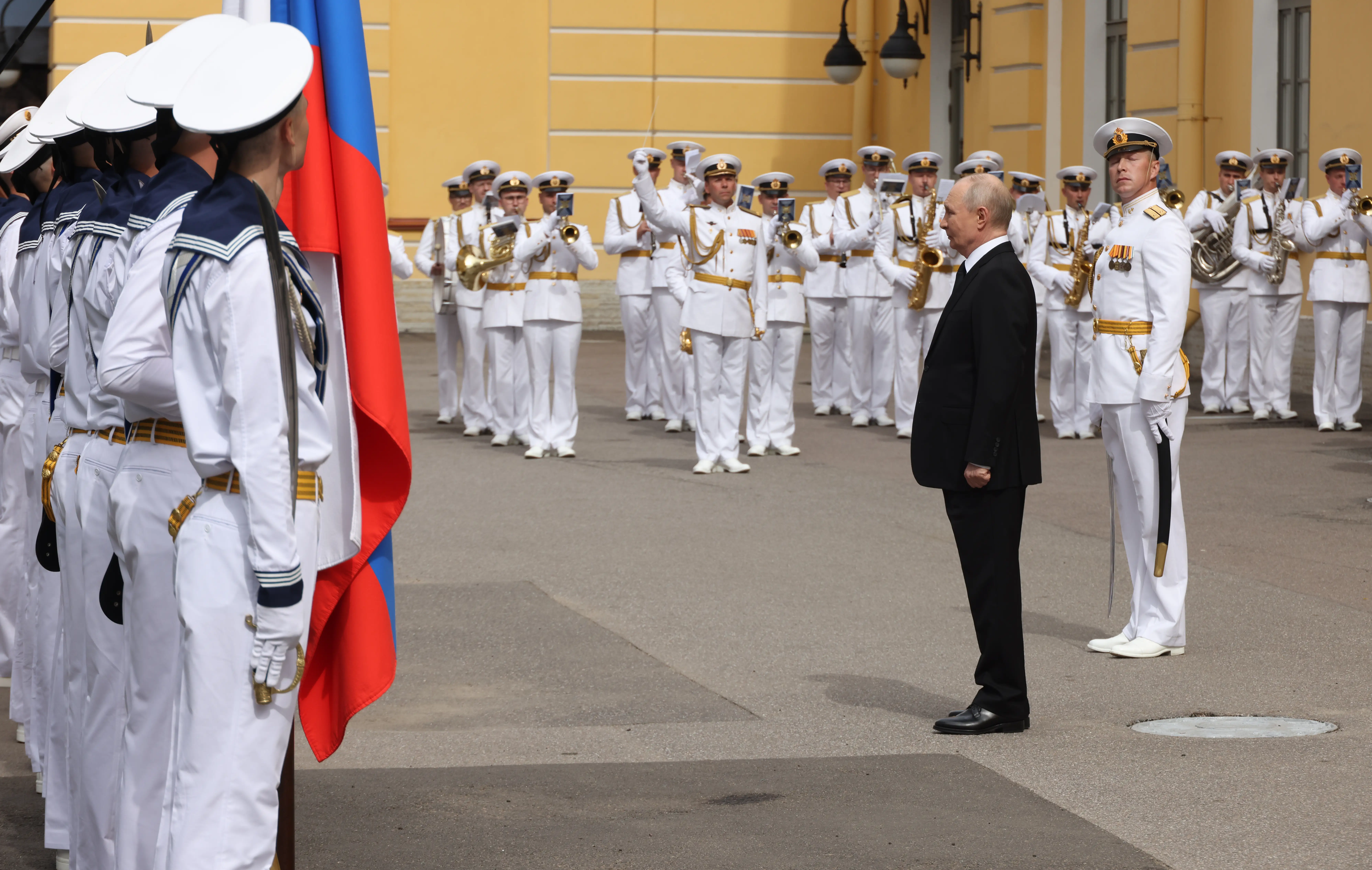Putin is received by a military band and several dozen sailors.