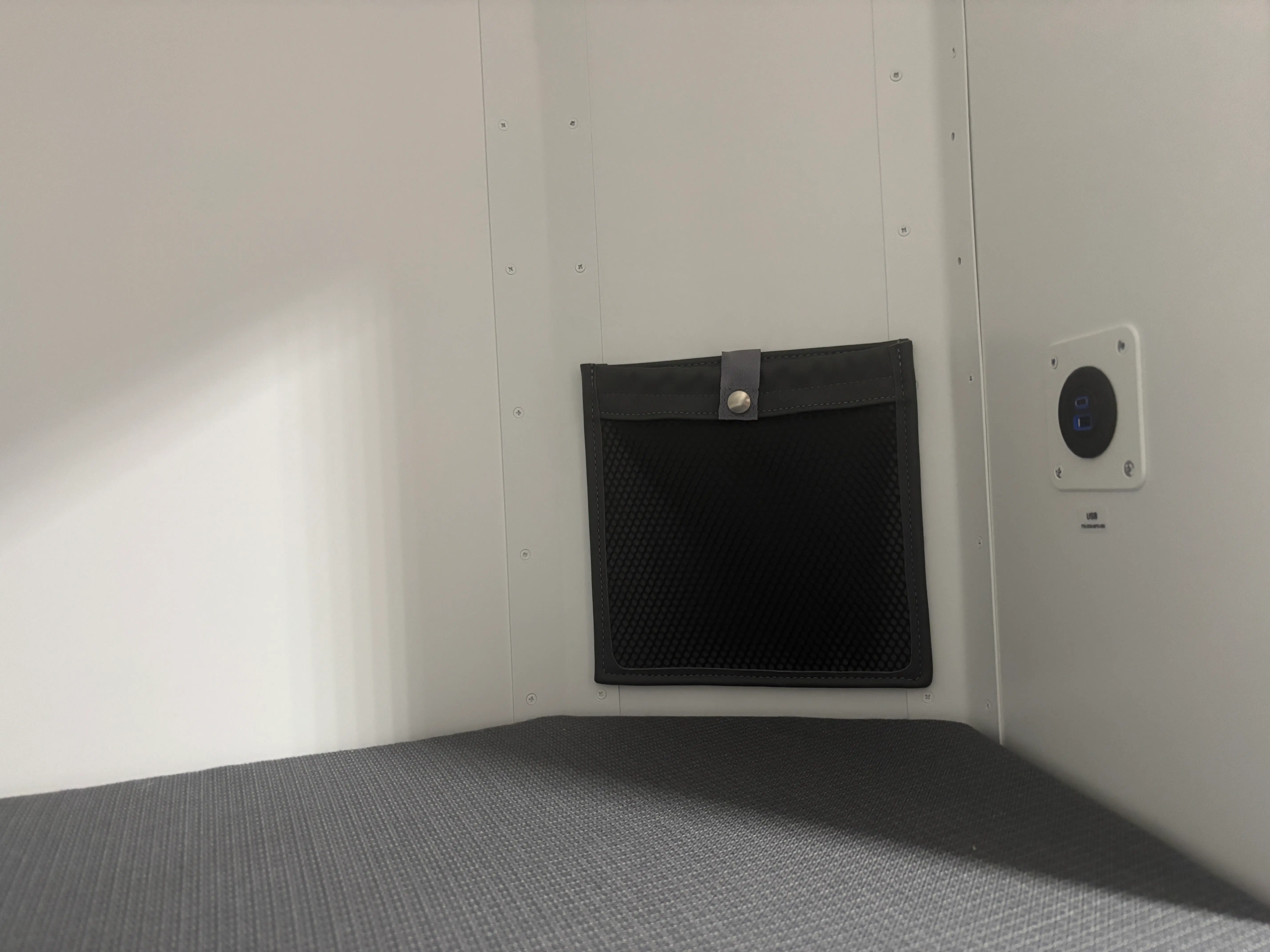 A glasses-holder pouch and USB charging outlet inside the crew rest area of a DHL Boeing 777