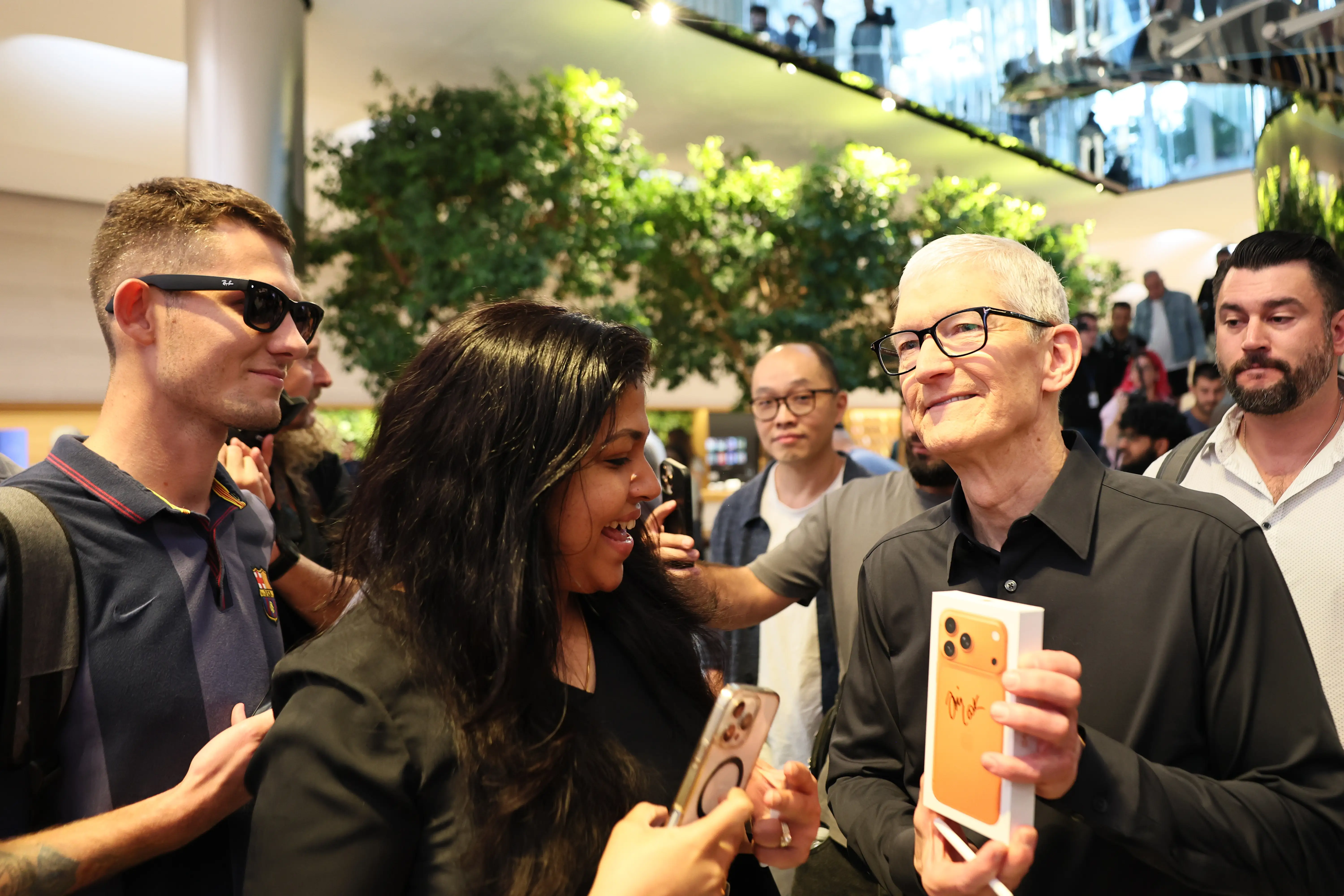 Apple CEO Tim Cook holds an autographed iPhone 17 Pro box in an Apple store.