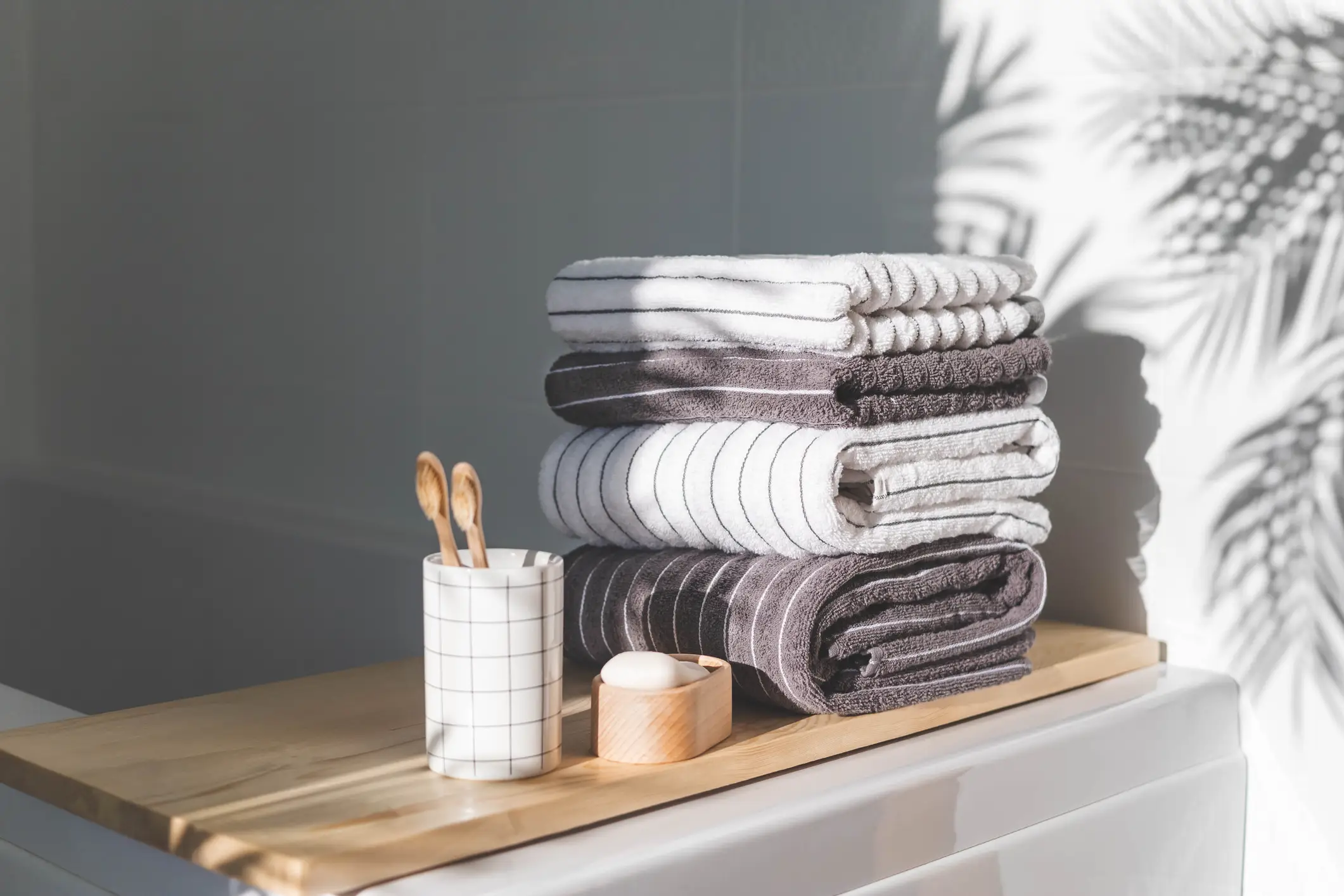 gray and white striped towels on wooden bath tray in bathroom