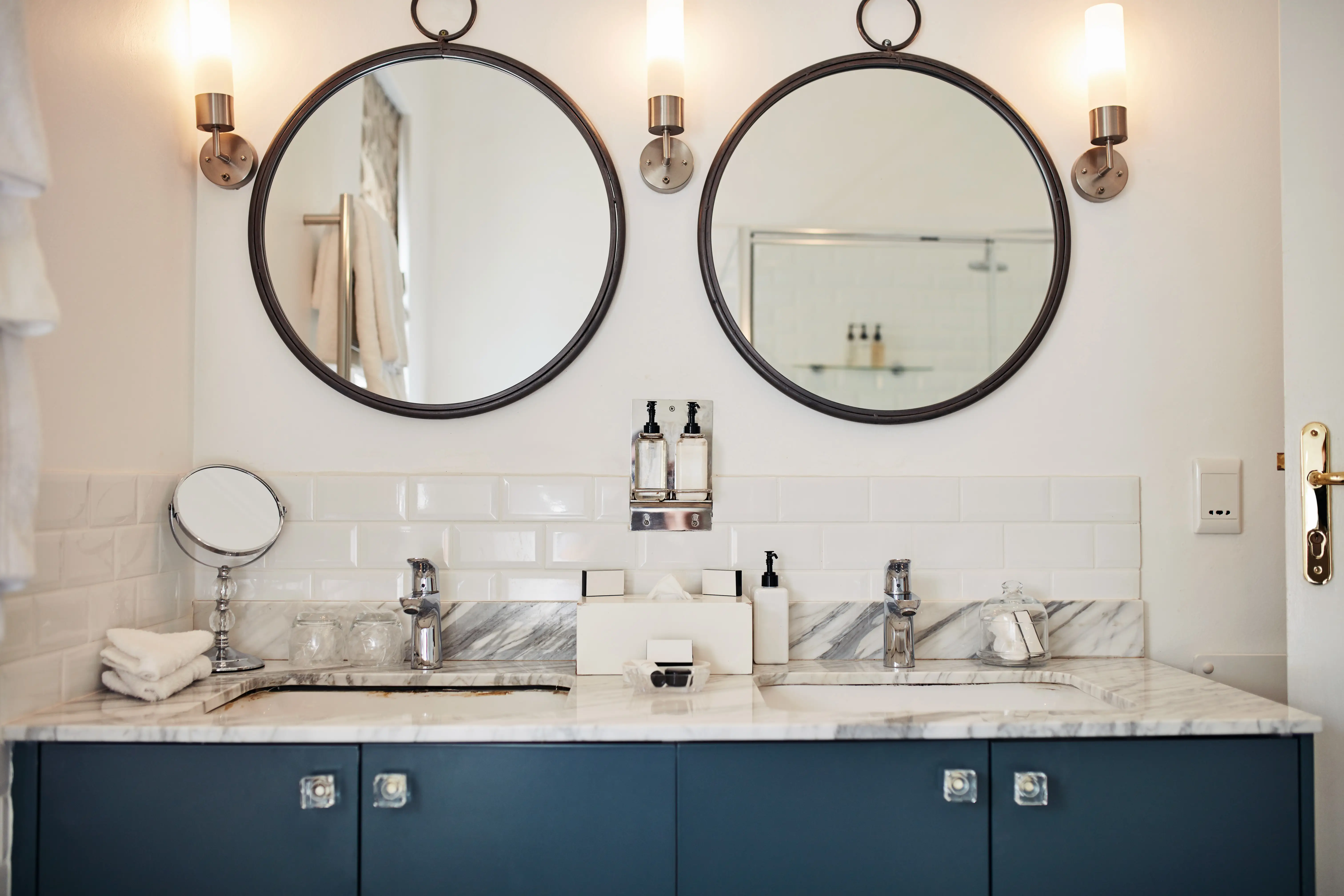 Bathroom with blue counters, two round mirrors, marble counters