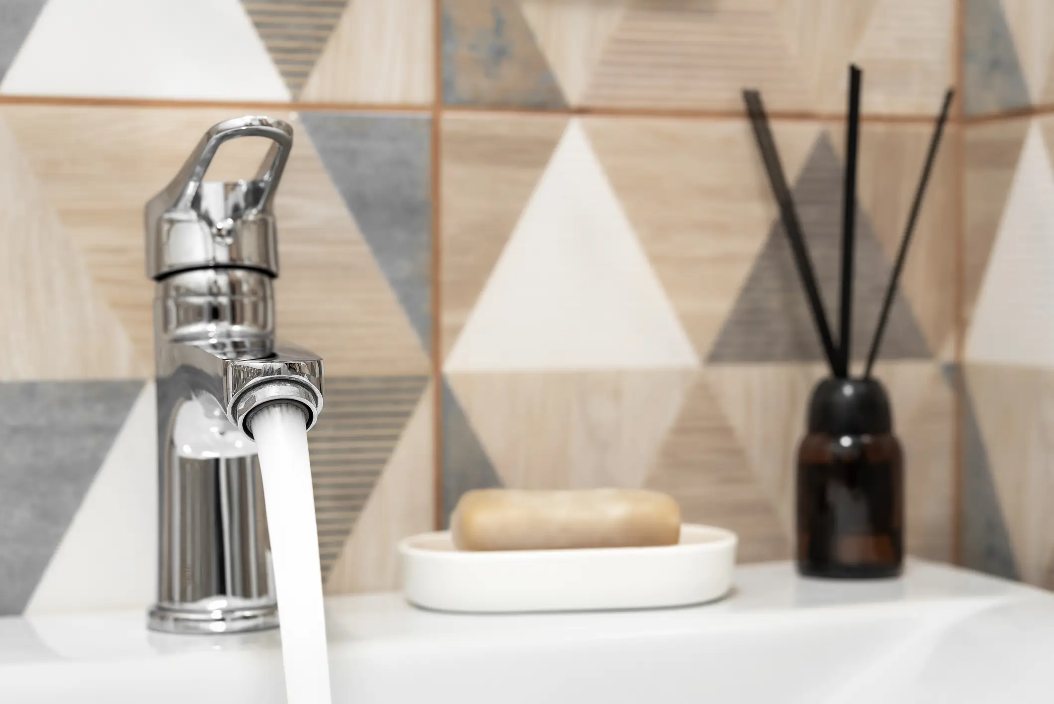 soap dish and diffuser next to running faucet