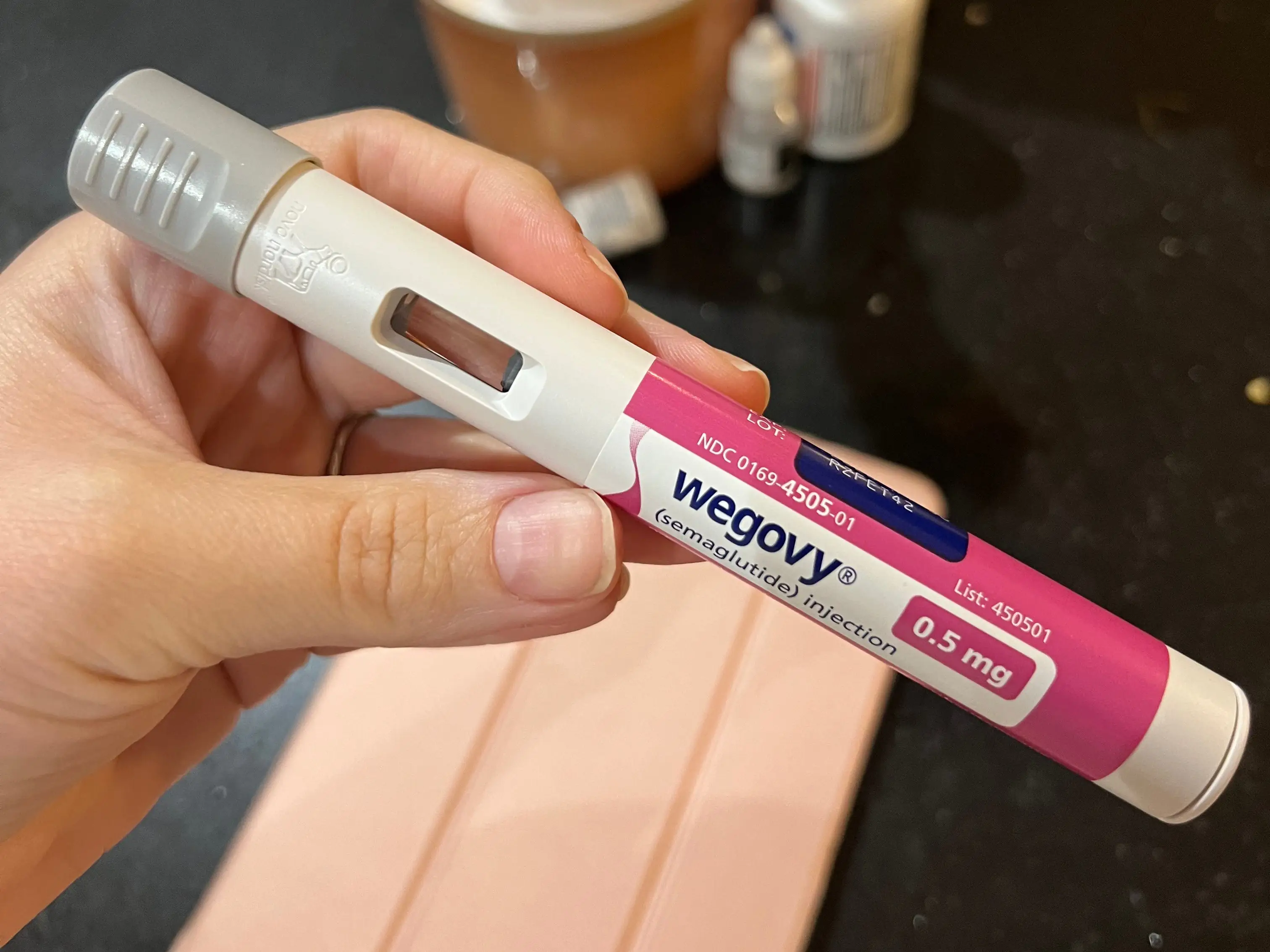 A hand holding a Wegovy injection.