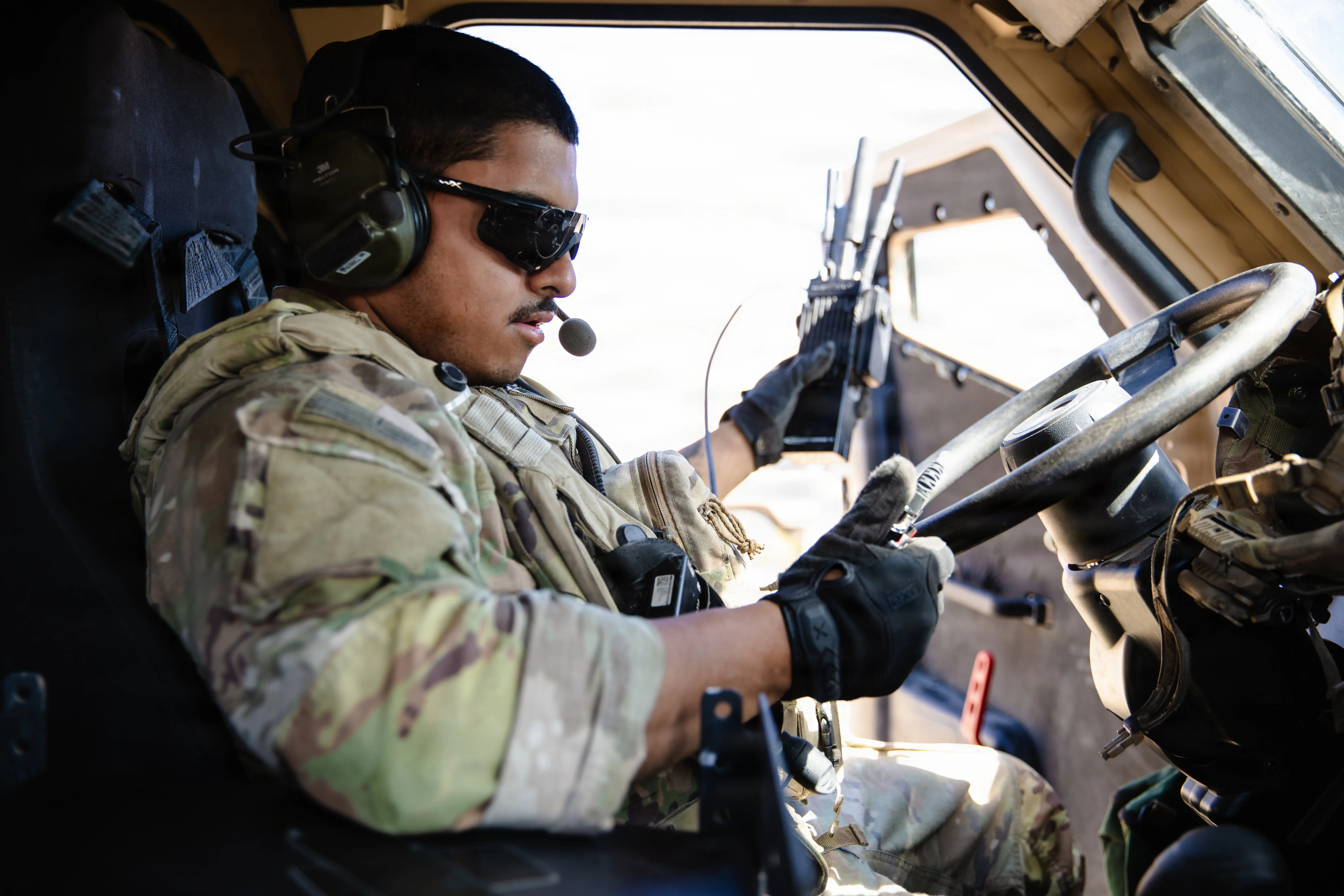 A US Army soldier holds an MPU5 radio inside a vehicle.