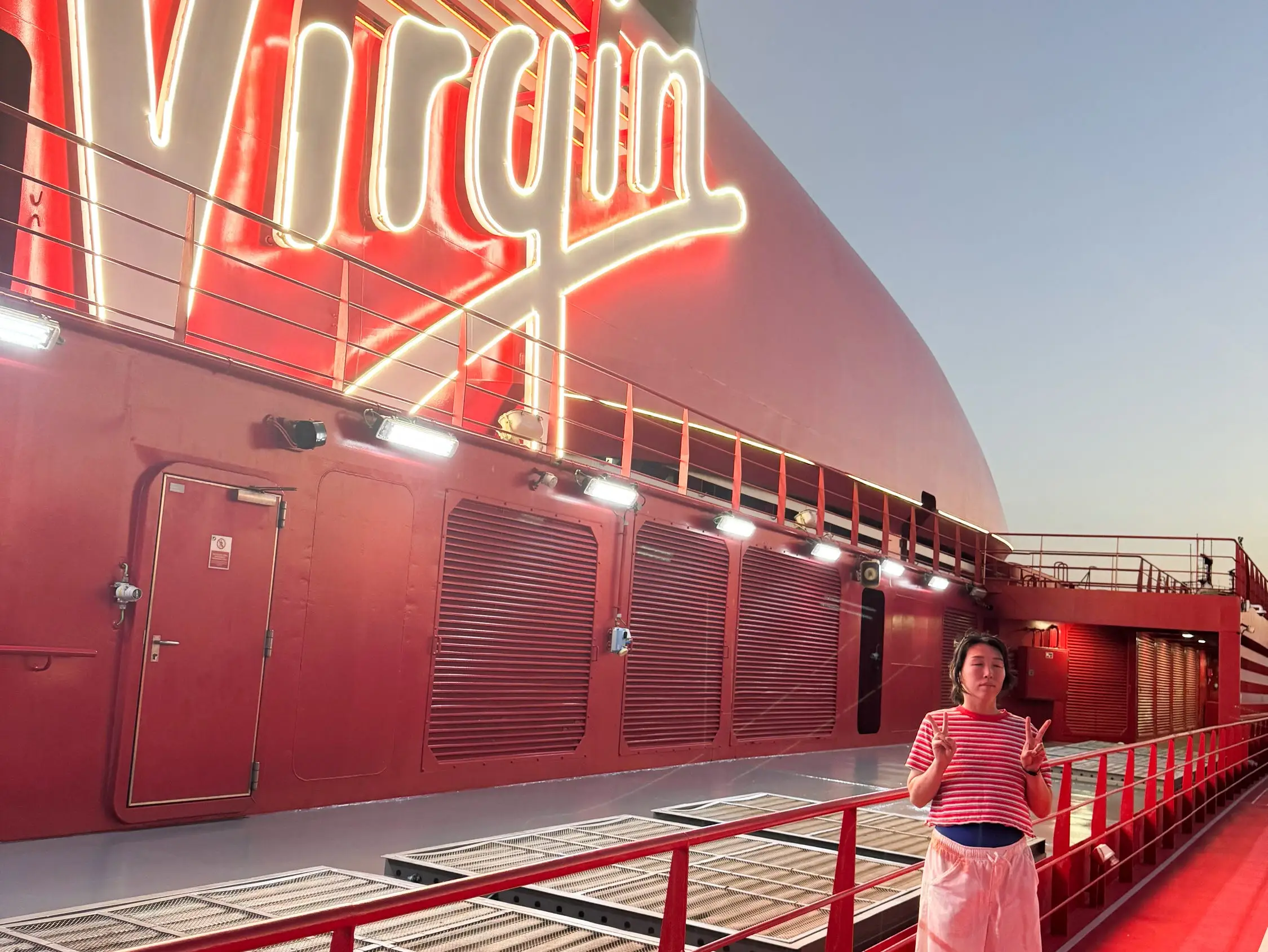 The writer poses on the deck of a Virgin Voyages cruise ship.