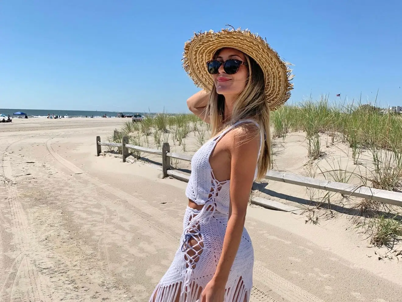 Alexa, wearing a sun hat and sunglasses, poses for a photo on the beach.
