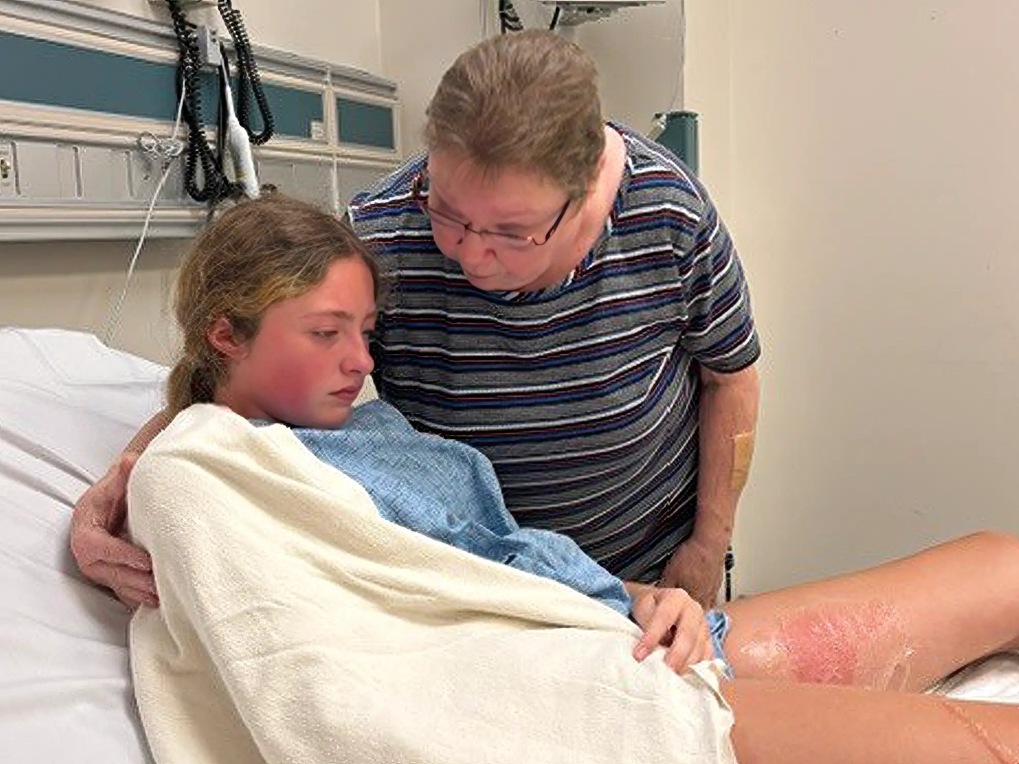 An older woman is comforting a young girl in the ER.