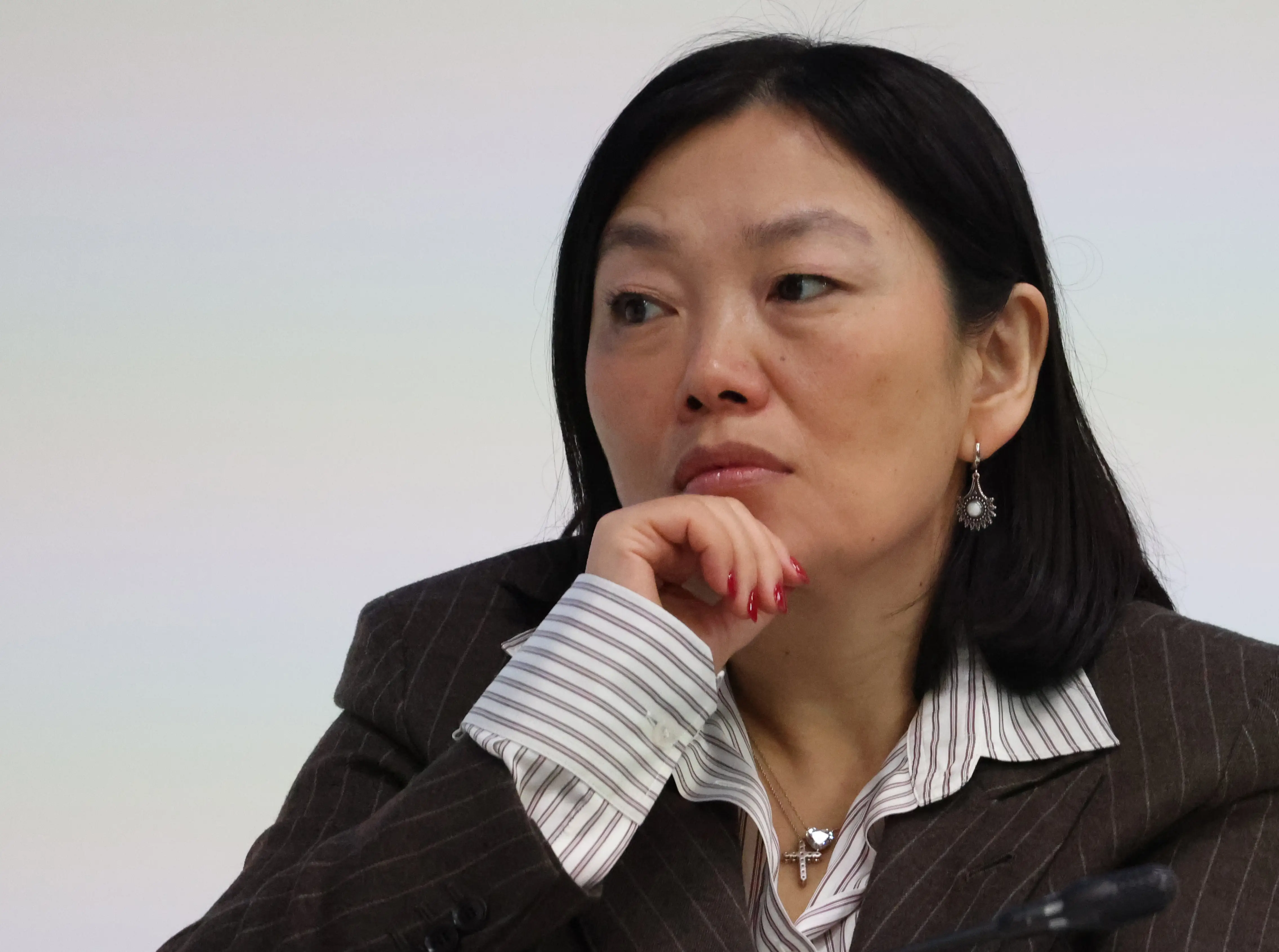 Tatyana Kim brushes her hand against her chin at a plenary.