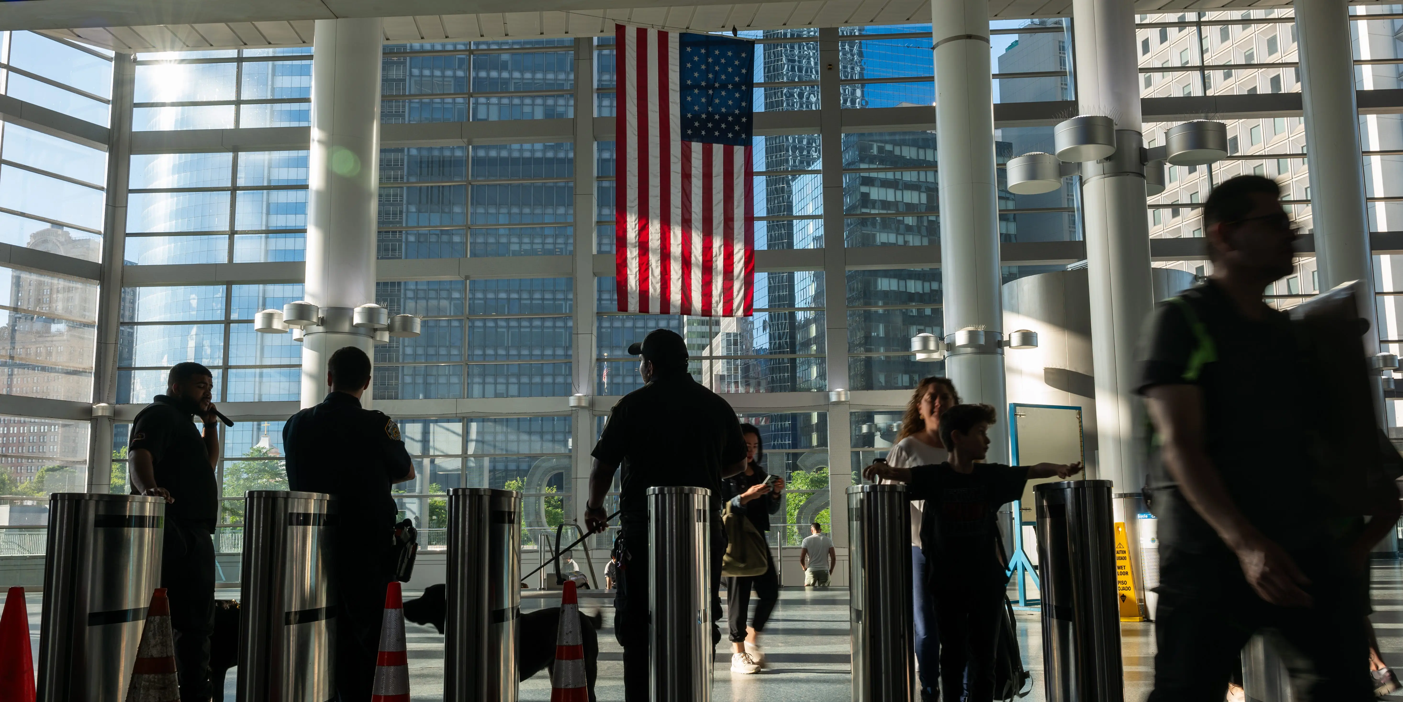People walking through a subway station in New York with the American flag hanging in the background