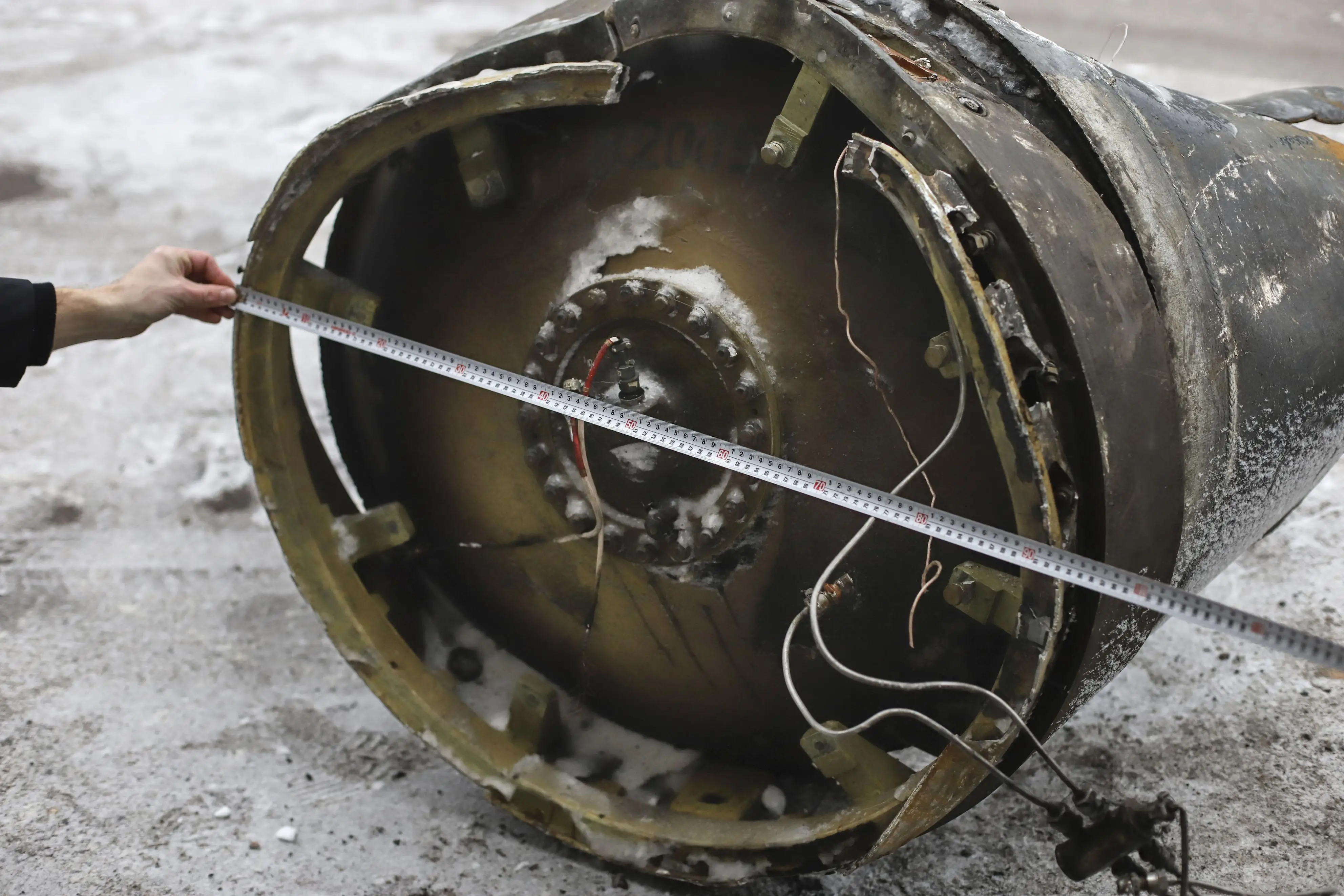 Measuring tape is drawn across debris from a KN-23 missile.
