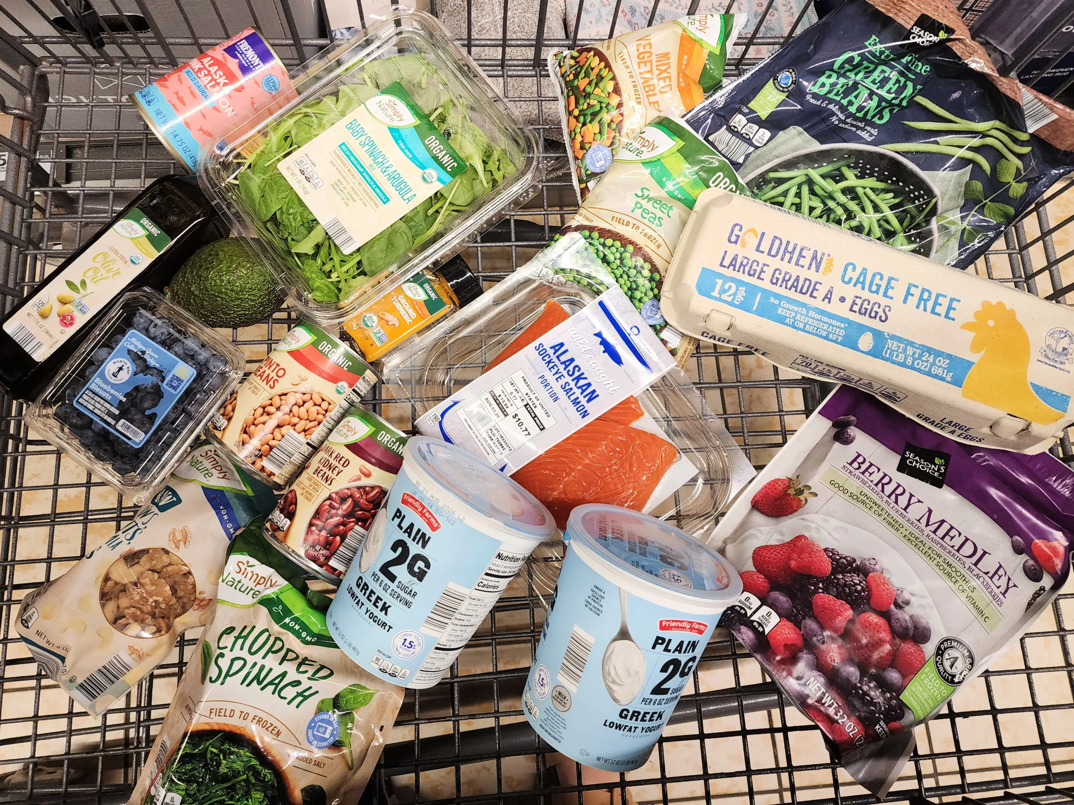 A cart full of anti-inflammatory groceries, including salmon, eggs, Greek yogurt, spinach, and olive oil from Aldi.