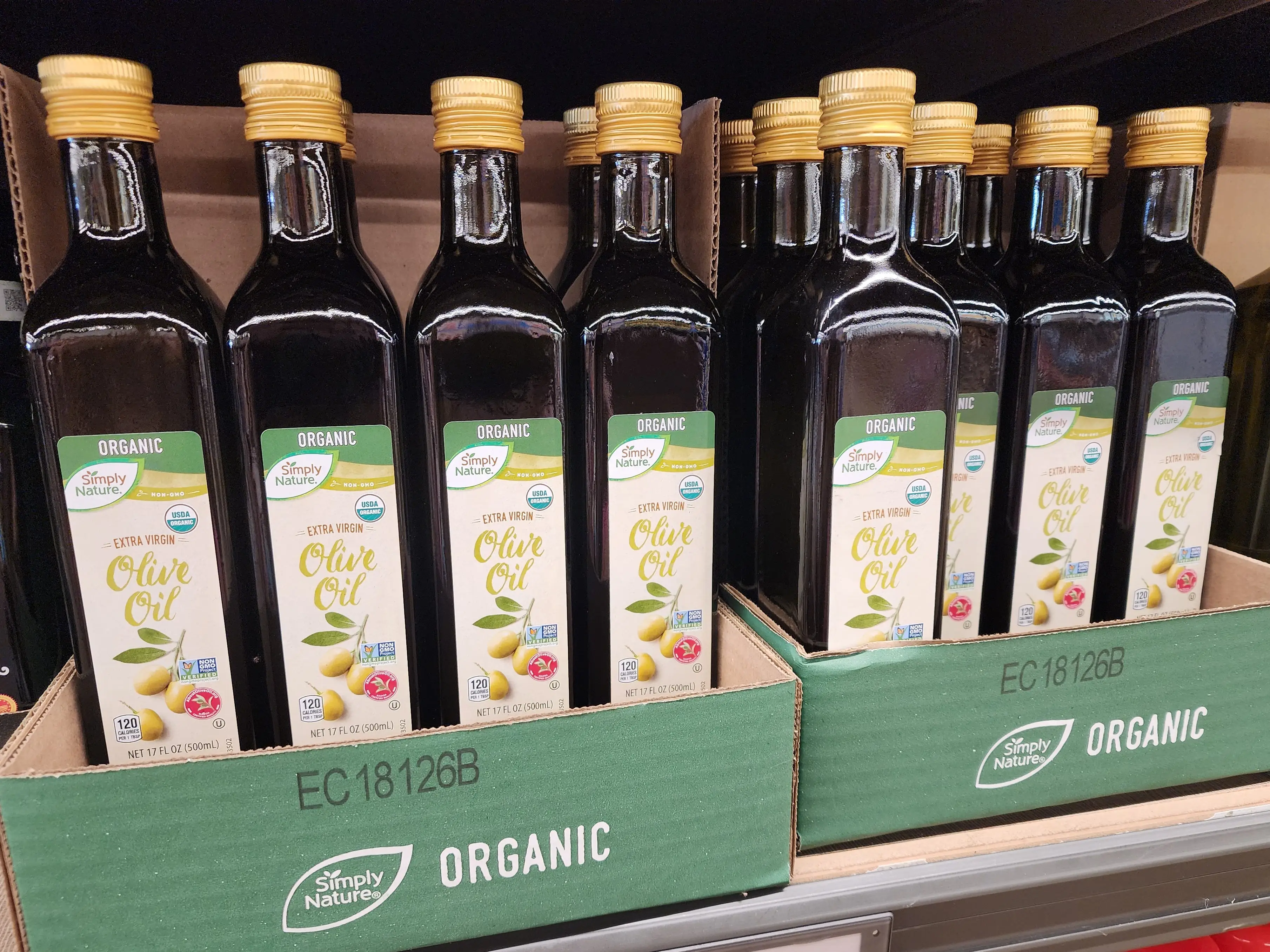Several bottles of Simply Nature organic extra-virgin olive oil sitting on a shelf at Aldi.