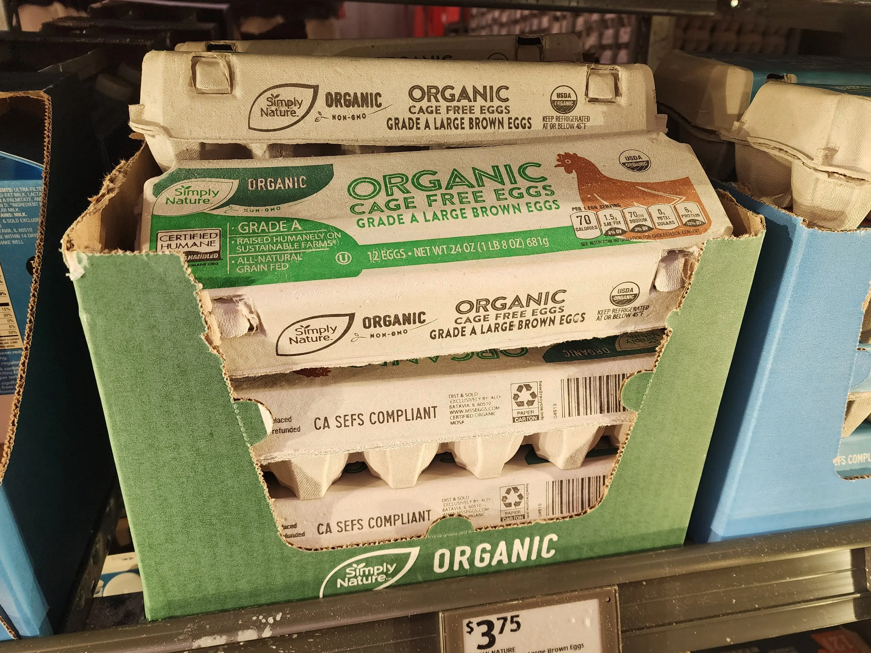 Several cartons of Simply Nature organic cage-free eggs sitting on a shelf at Aldi.