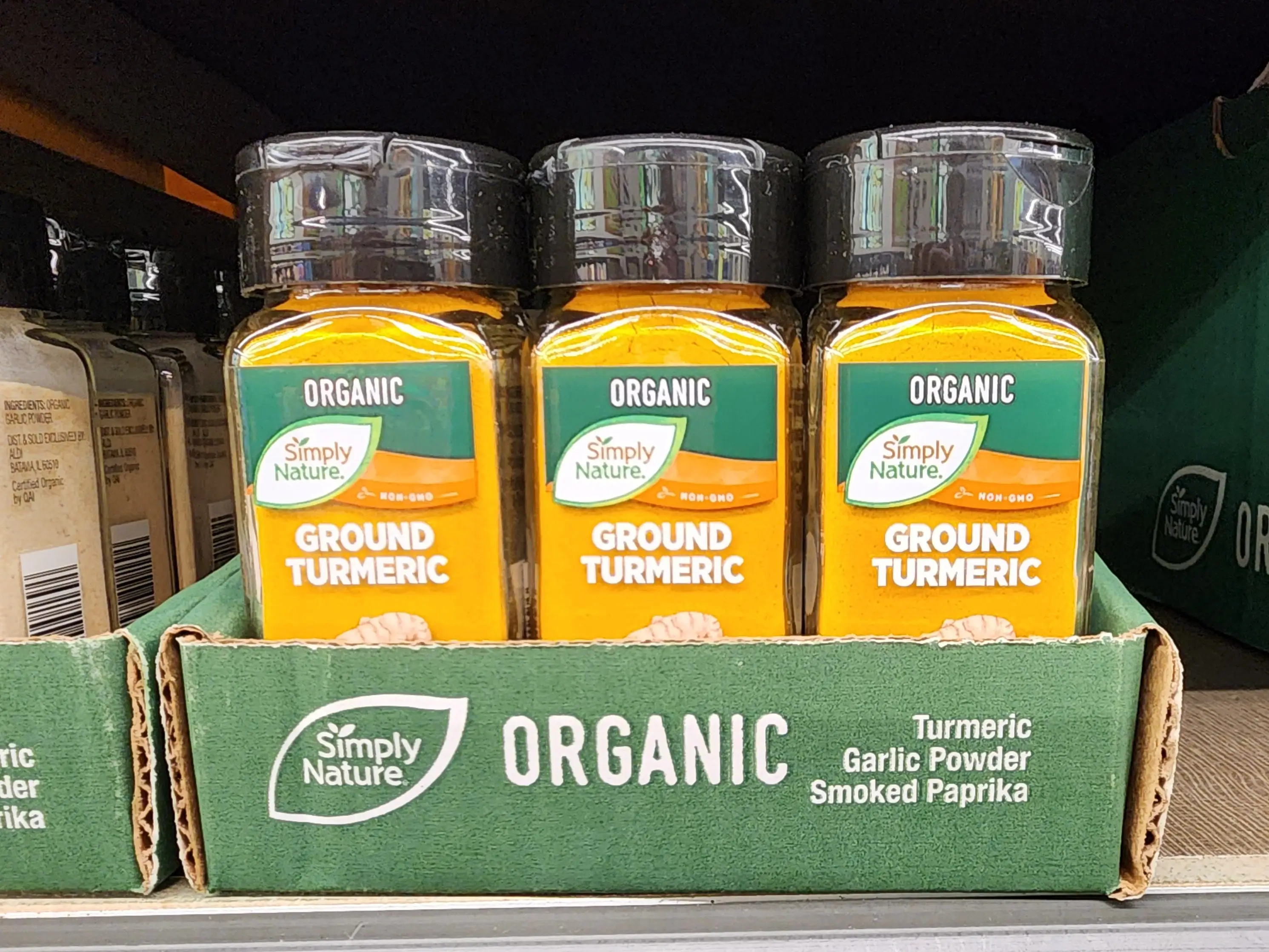 Several bottles of Simply Nature organic ground turmeric sit on a shelf at Aldi.