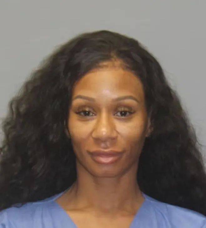 Mugshot of a woman with long, dark, wavy hair and a light blue top.