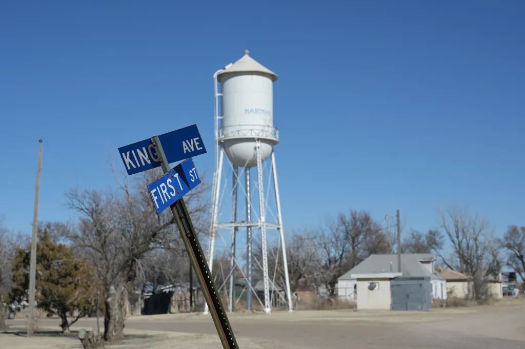 Street signs for King Ave and First St with a water tower in the background.