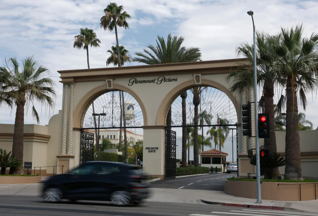 The Melrose Gate entrance to Paramount Pictures, with a car in motion and a red traffic light.
