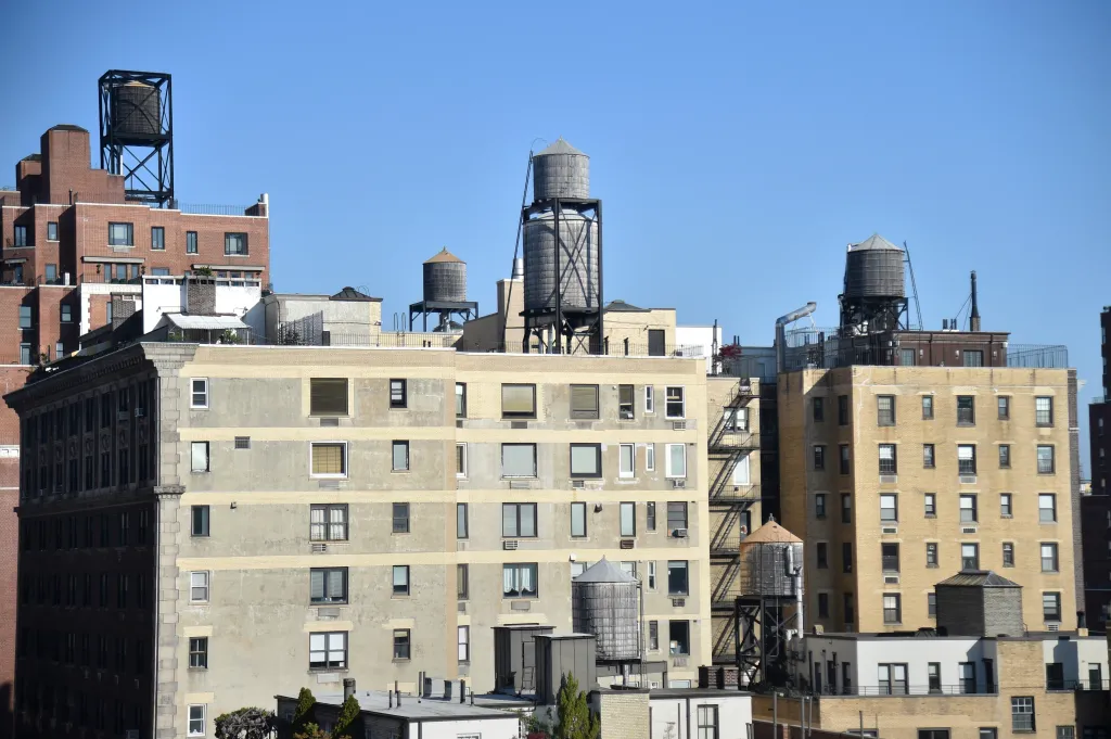 Multiple water towers on the rooftops of urban buildings.