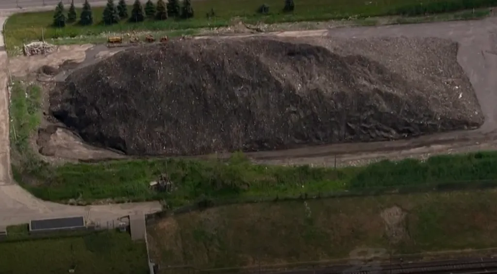 Aerial view of a large, dark pile of waste at a landfill.