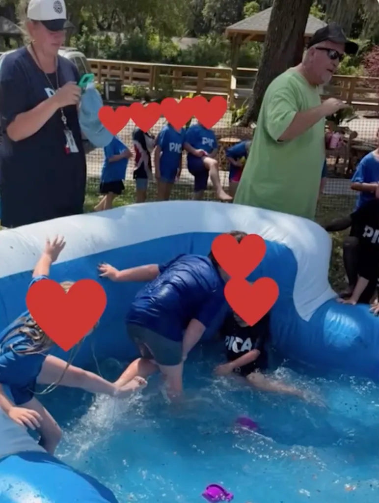 People in an inflatable pool and on the surrounding grass area.