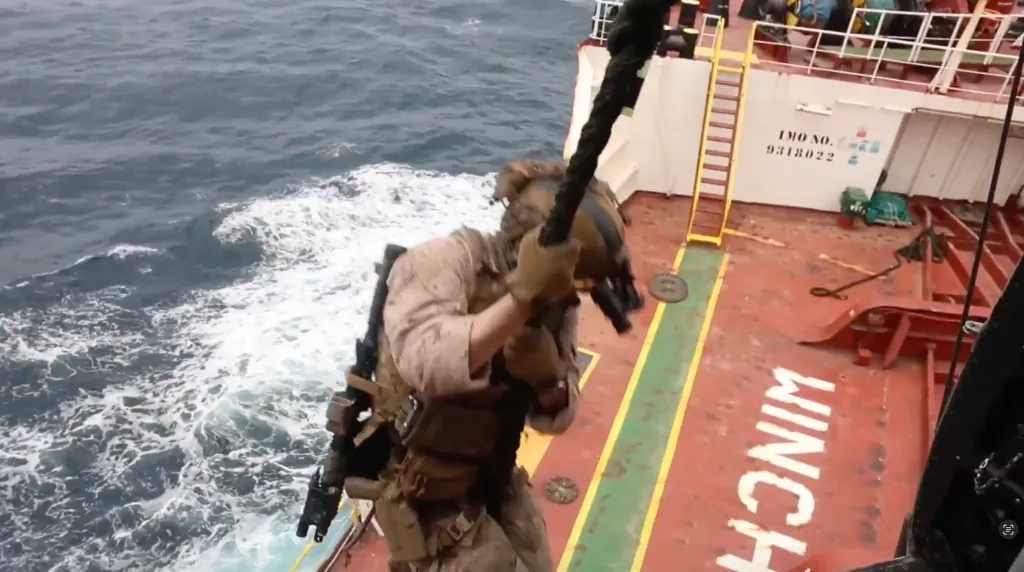 A soldier rappelling onto a ship from above.