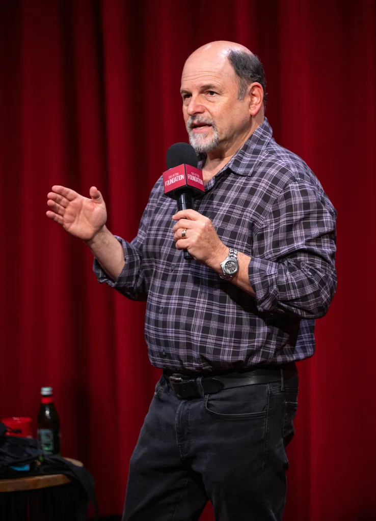 Actor Jason Alexander speaking into a microphone.