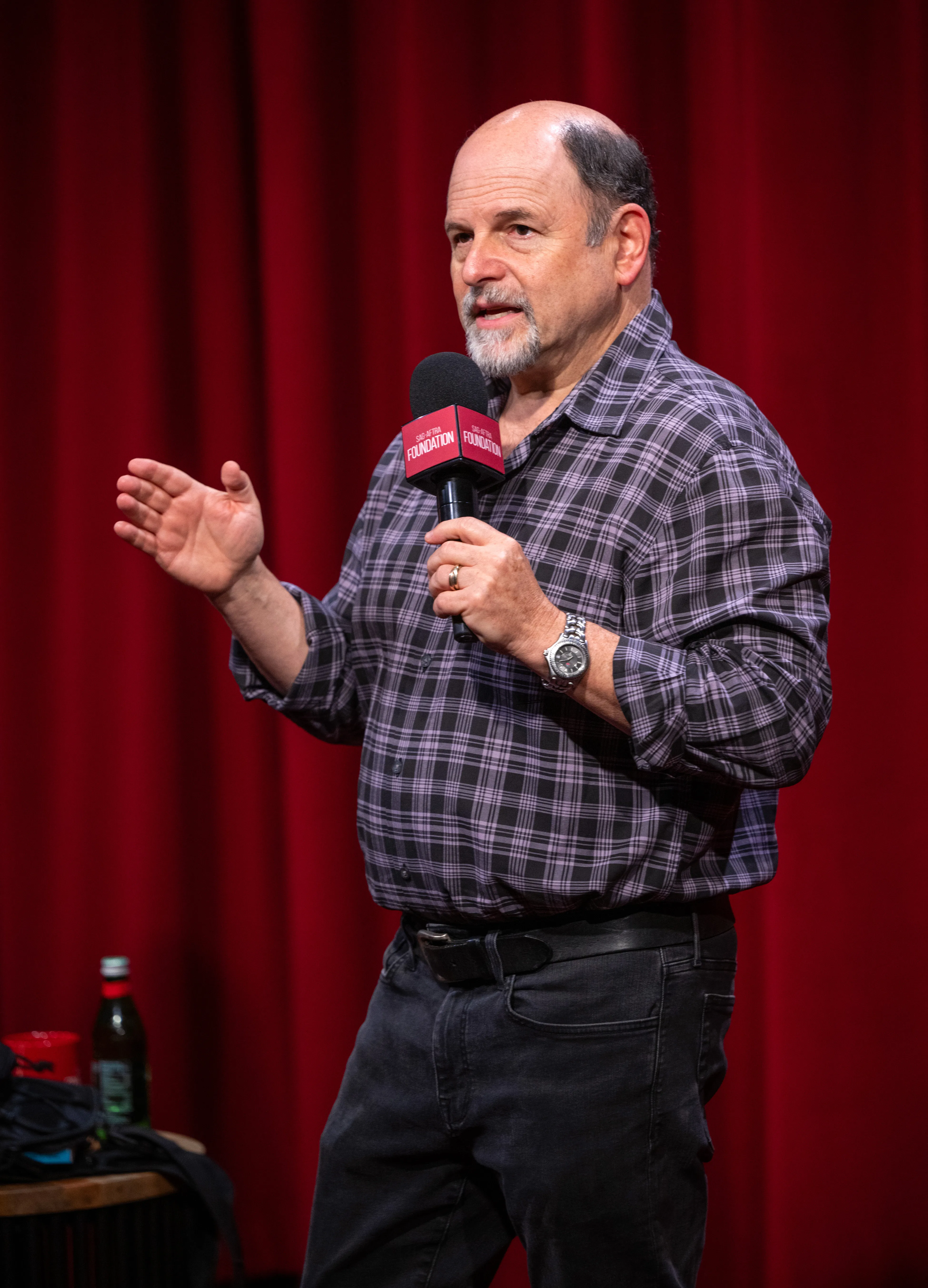 Jason Alexander speaking into a microphone.