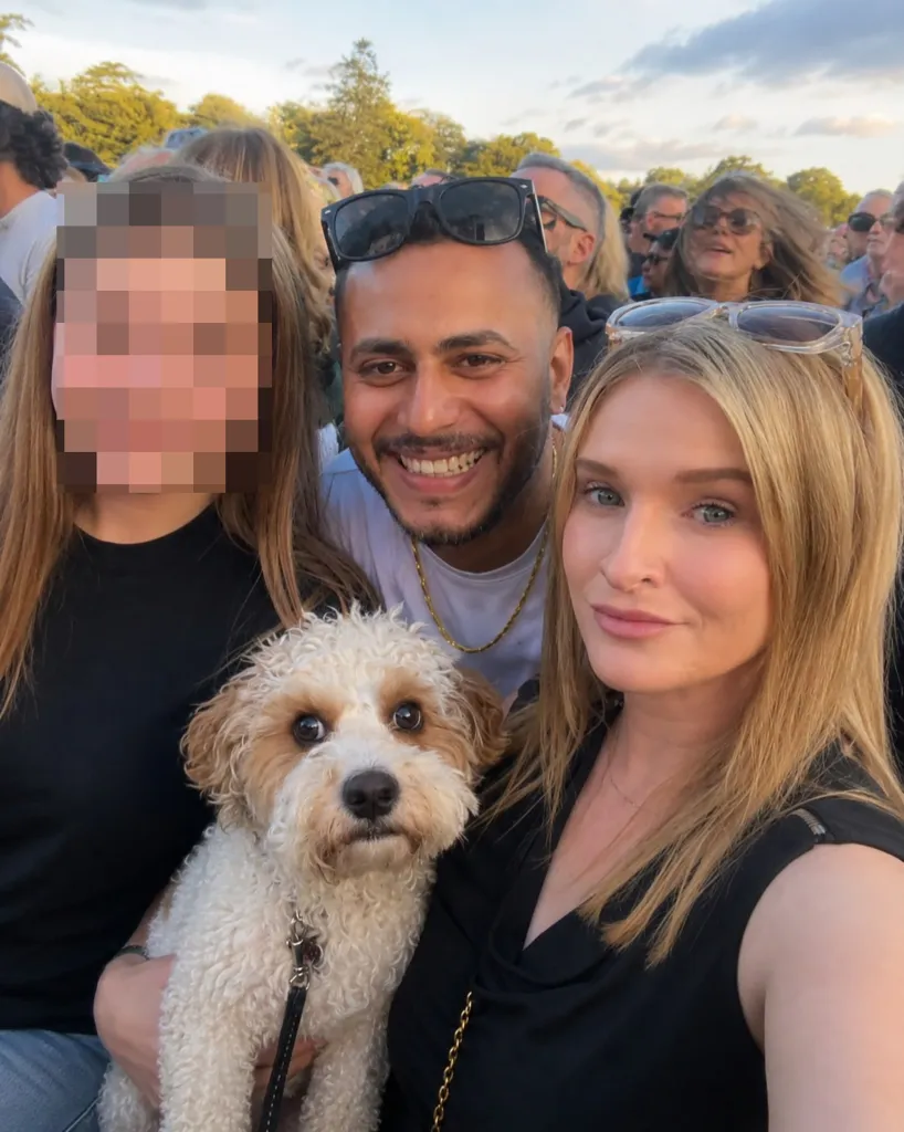 A man smiling between two women, one holding a dog, possibly at an anti-war protest.