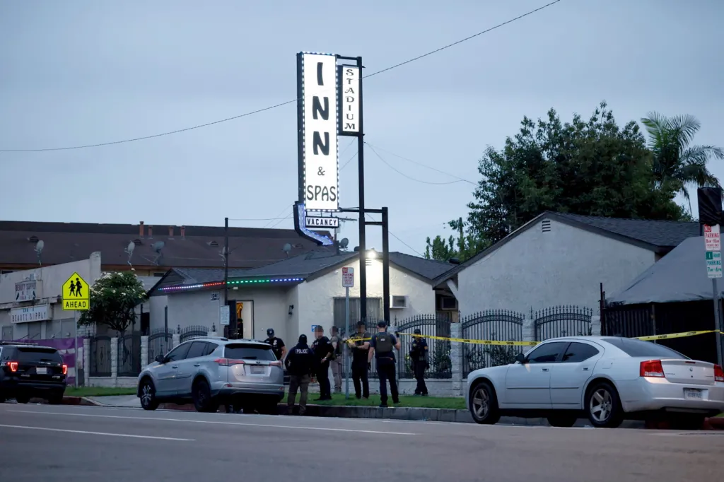Police officers stand outside a motel with a