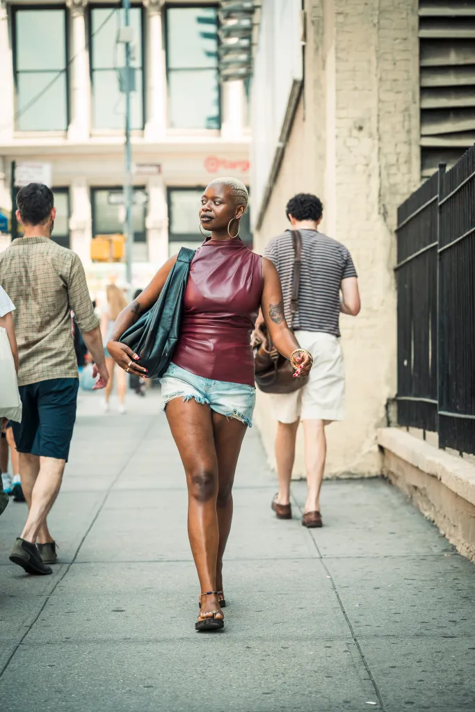 Ashley Renée walking on W Houston St, Manhattan, in a burgundy top and cut-off denim shorts.