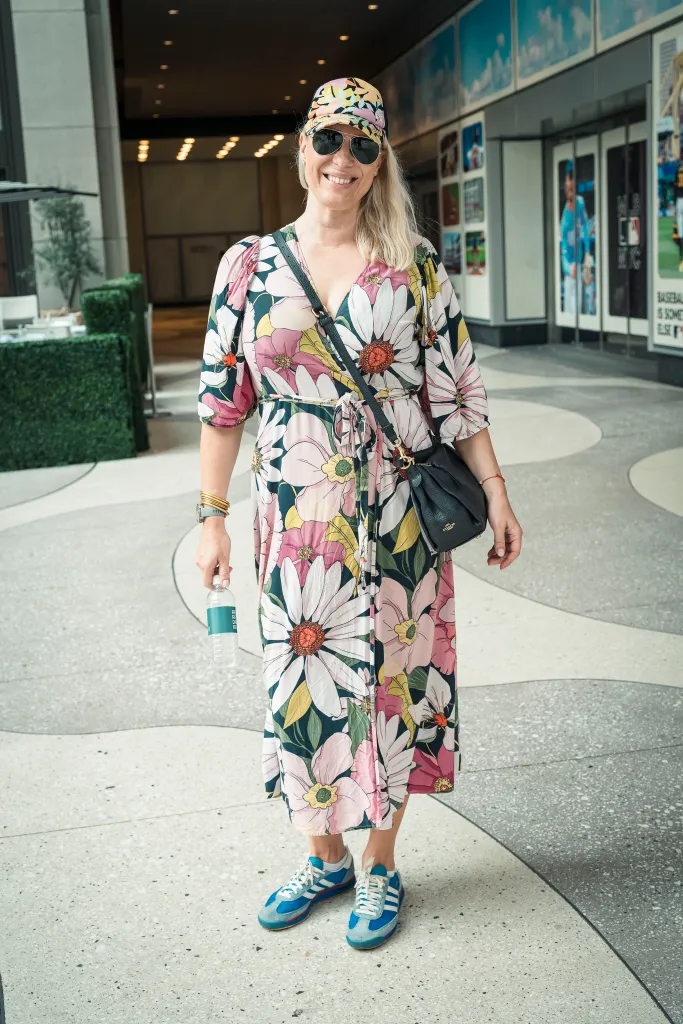 Barbara Sklodowska in Midtown, Manhattan, wearing a floral dress, cap, and sneakers.