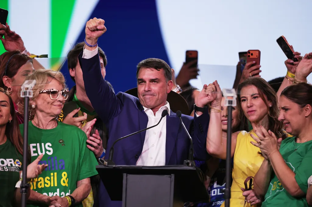 Brazilian Sen. Flavio Bolsonaro and his wife Fernanda raise their arms at a Liberal Party convention.