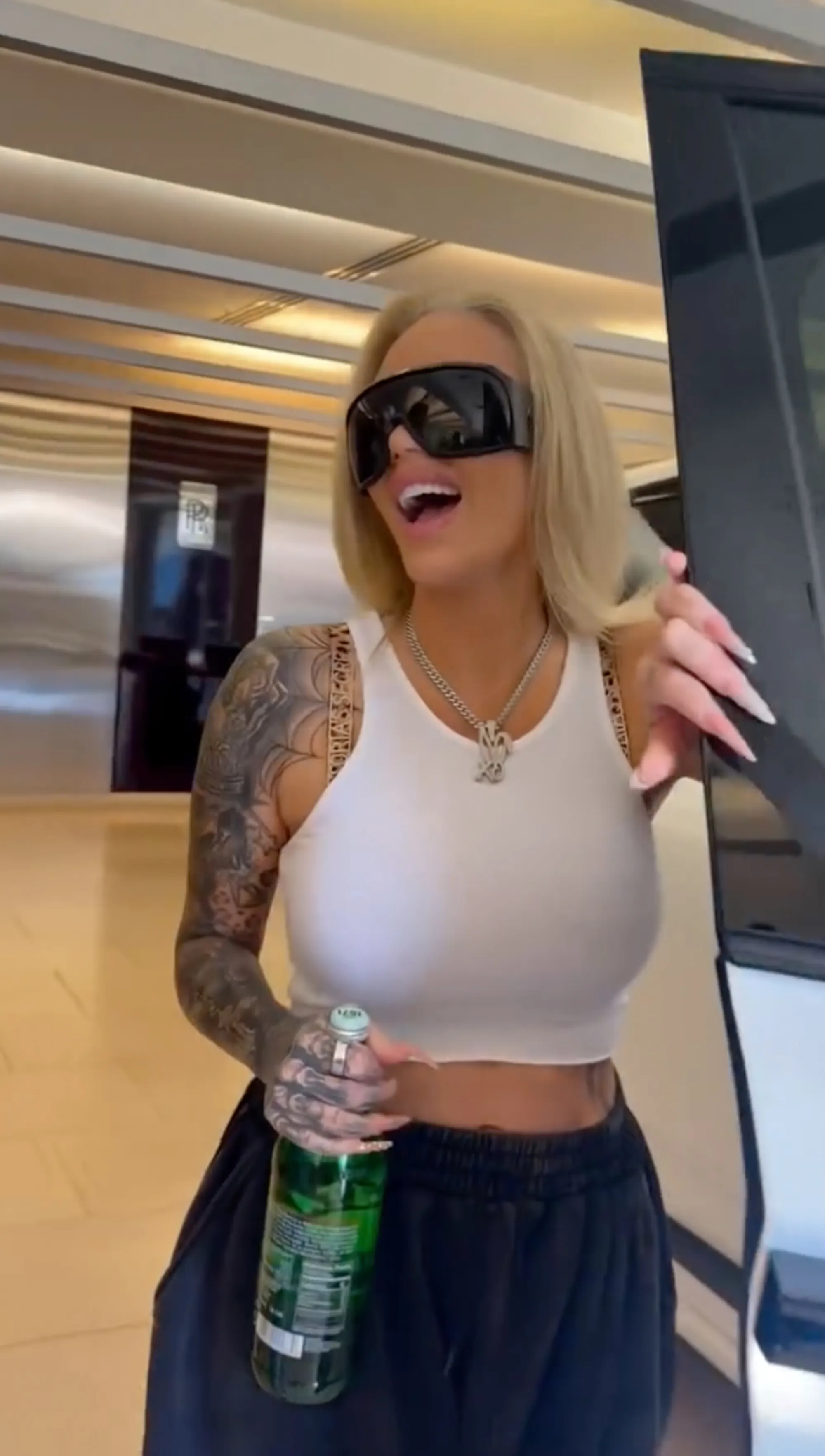Bunnie Xo holding a bottle while getting into a Rolls-Royce.