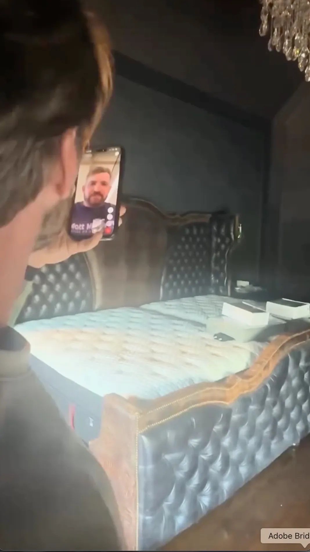 A person holding up a phone with a video call open to show a gigantic bed.