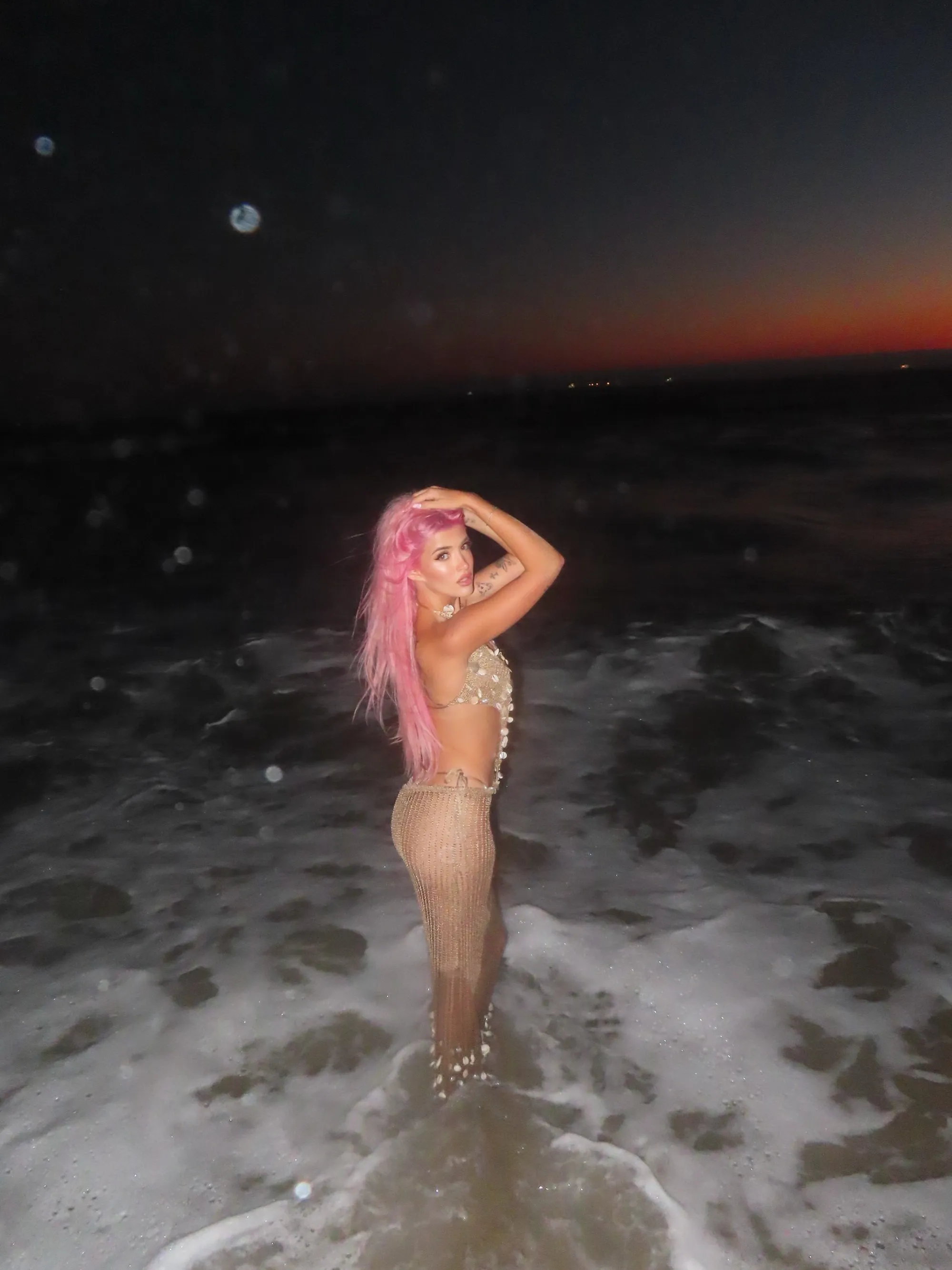 Sami Sheen in the ocean at sunset, wearing a crocheted top and skirt.