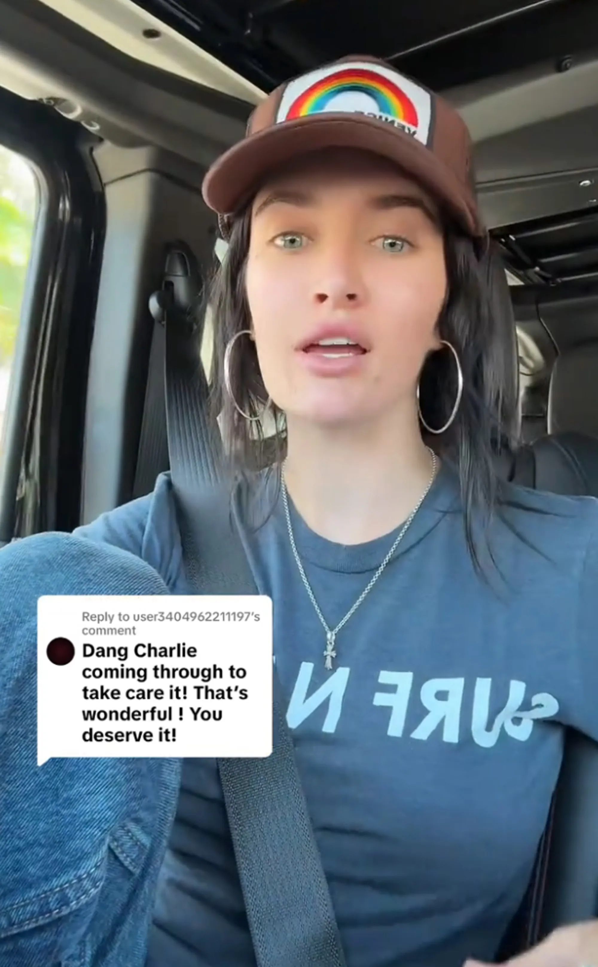 Sami Sheen in a car, wearing a rainbow-patch hat, gray t-shirt, and hoop earrings, with a speech bubble showing a comment about her father, Charlie, taking care of her.
