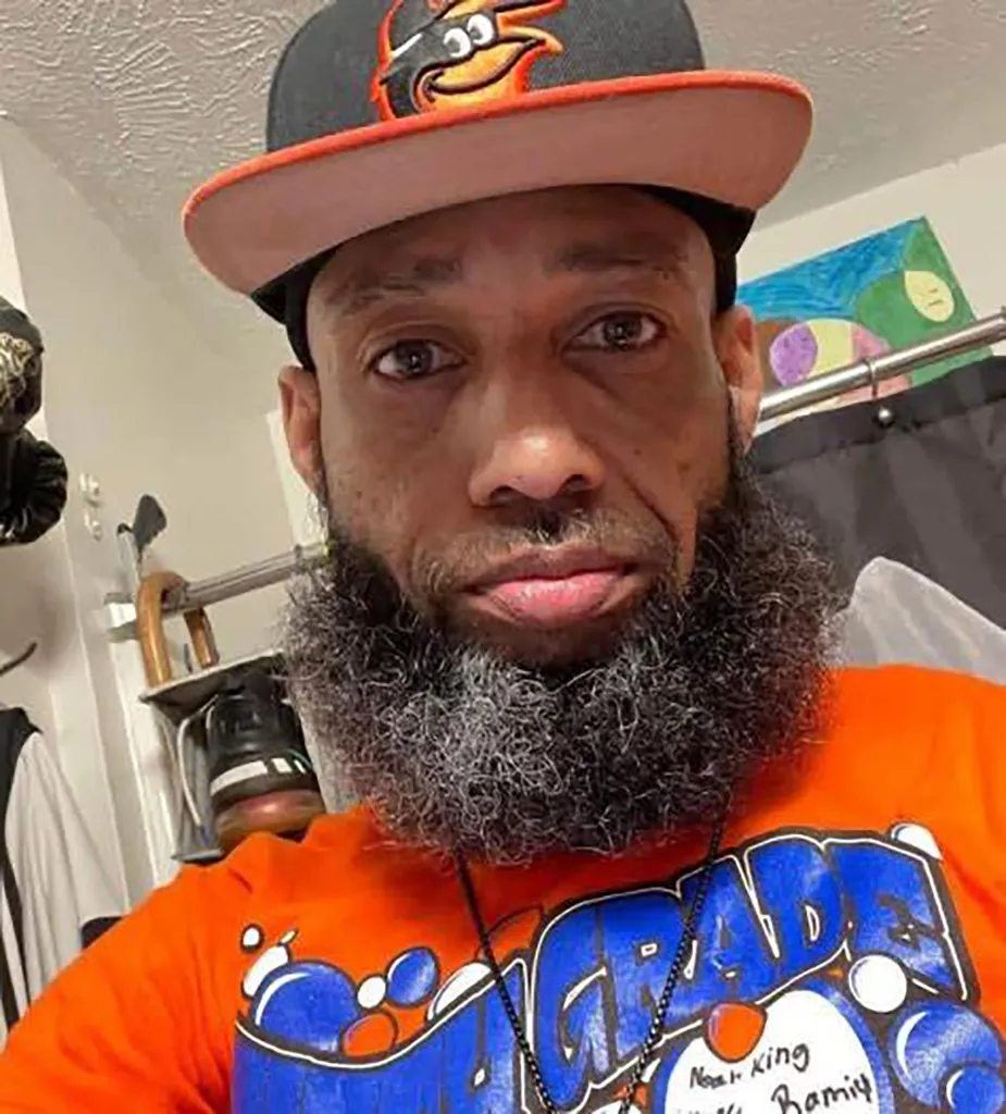 Chauncey Newman, a man with a graying beard, wearing an orange and black cap and an orange t-shirt.