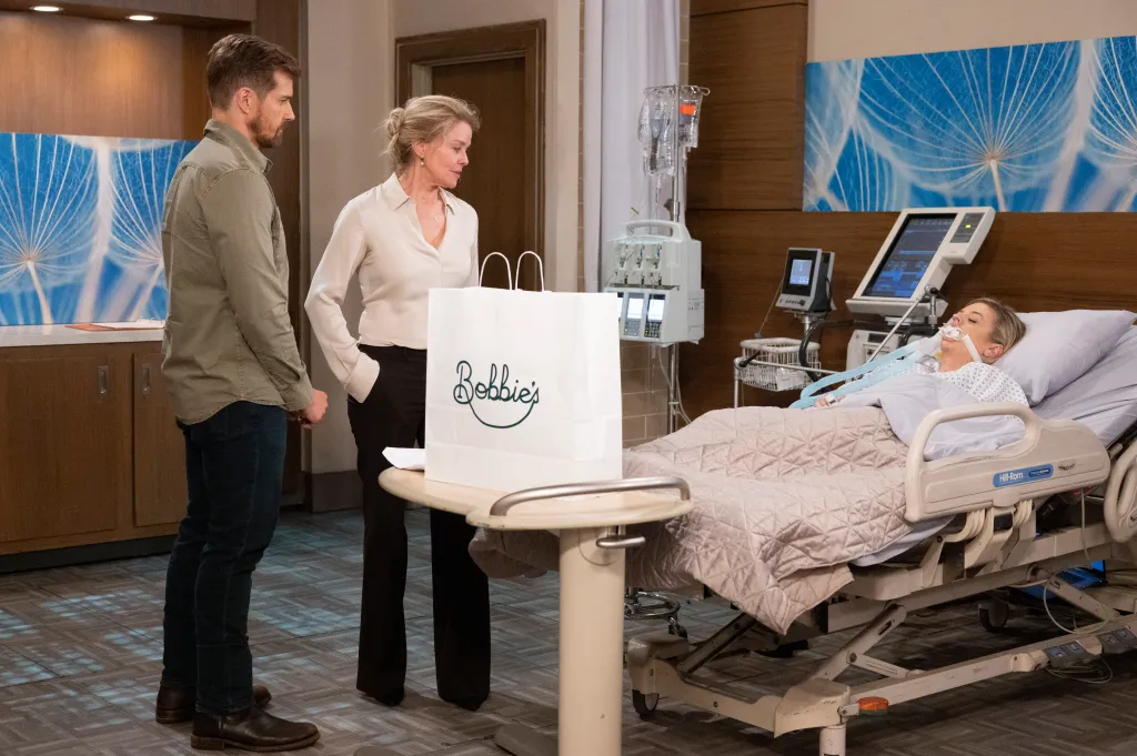 Josh Kelly and Kristina Wagner stand by Kirsten Storms who is in a hospital bed.