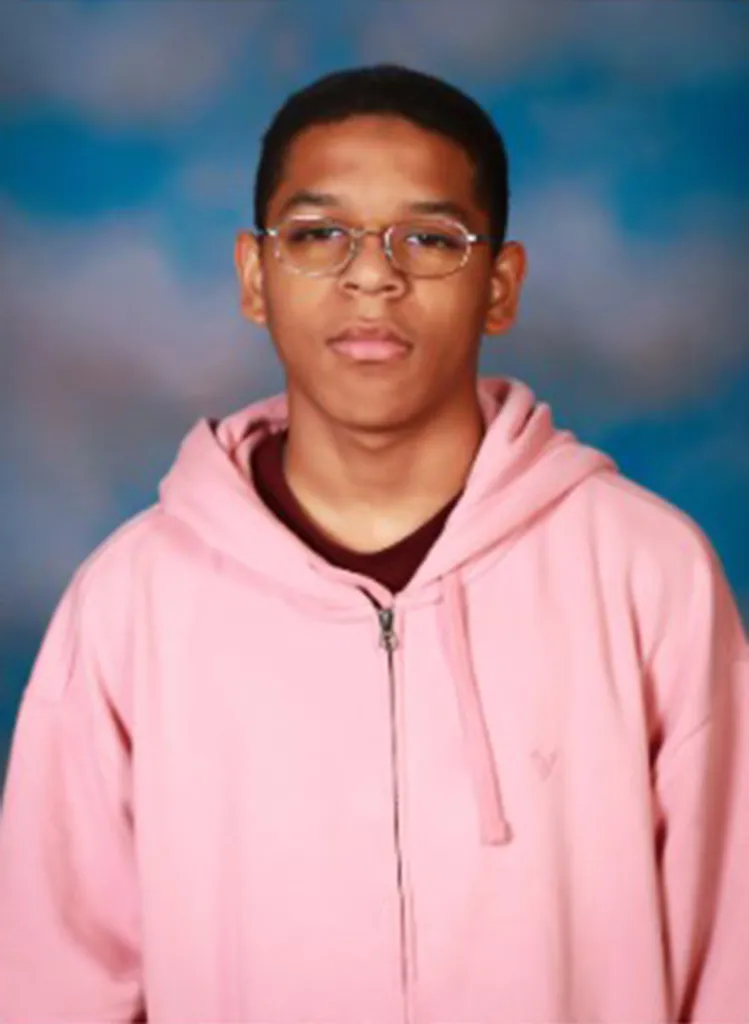 Mason Schermerhorn, a young man with glasses, wearing a pink zippered hoodie and burgundy shirt, looking directly at the camera.