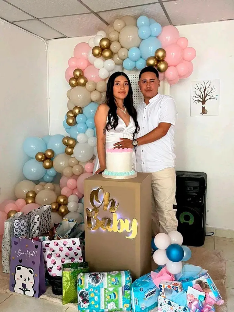 A man and a pregnant woman stand beside a 