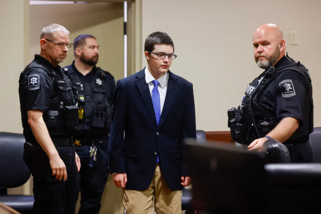 Colt Gray, a 16-year-old high school shooting suspect, is led into a plea hearing by two deputies.